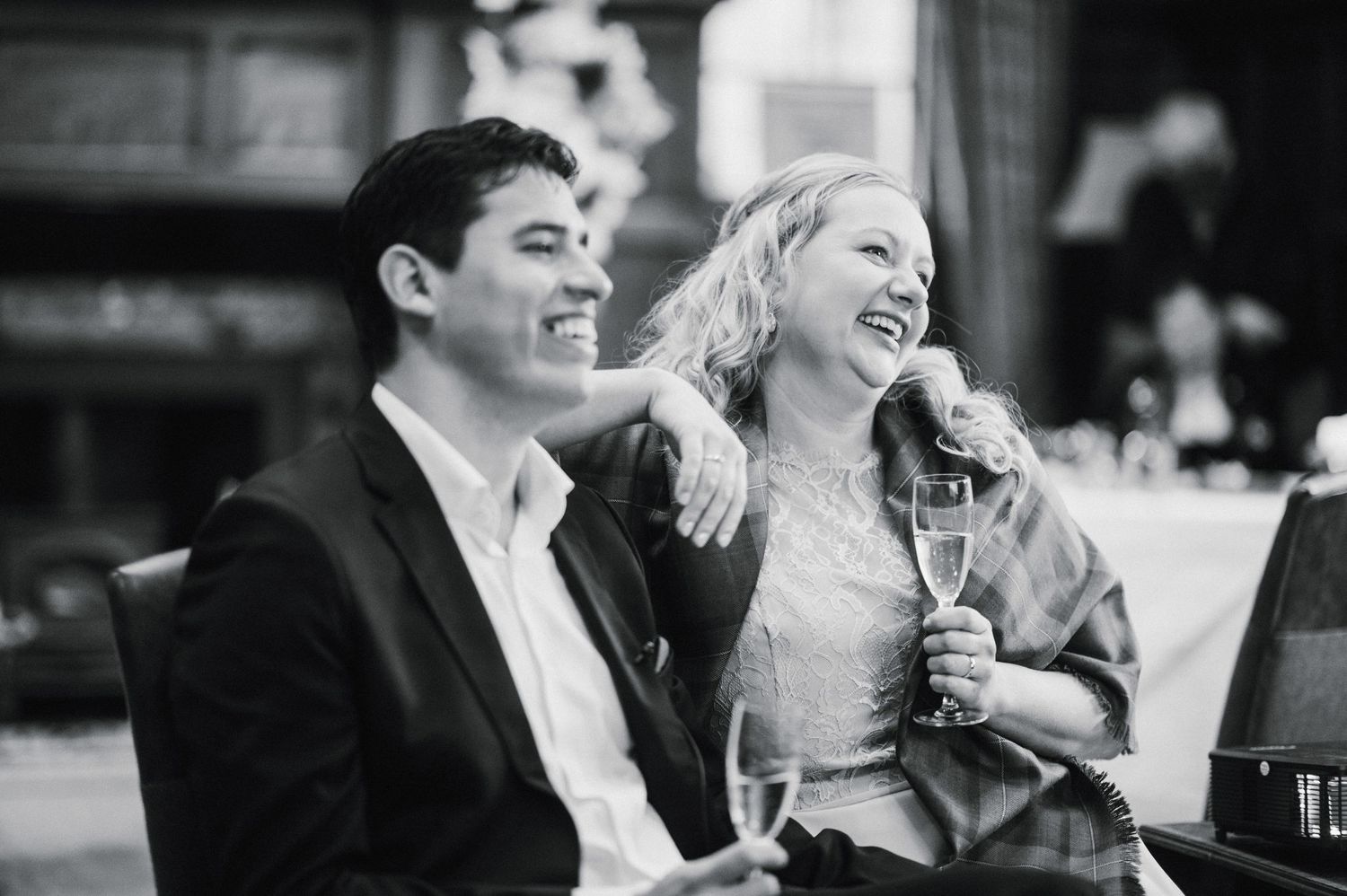 A black and white photo captures a candid moment of laughter between a couple.