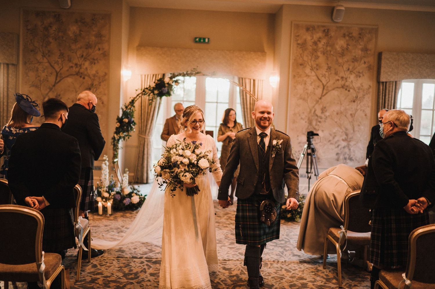 Wedding couple walking down the aisle in a beautifully decorated ceremony room.