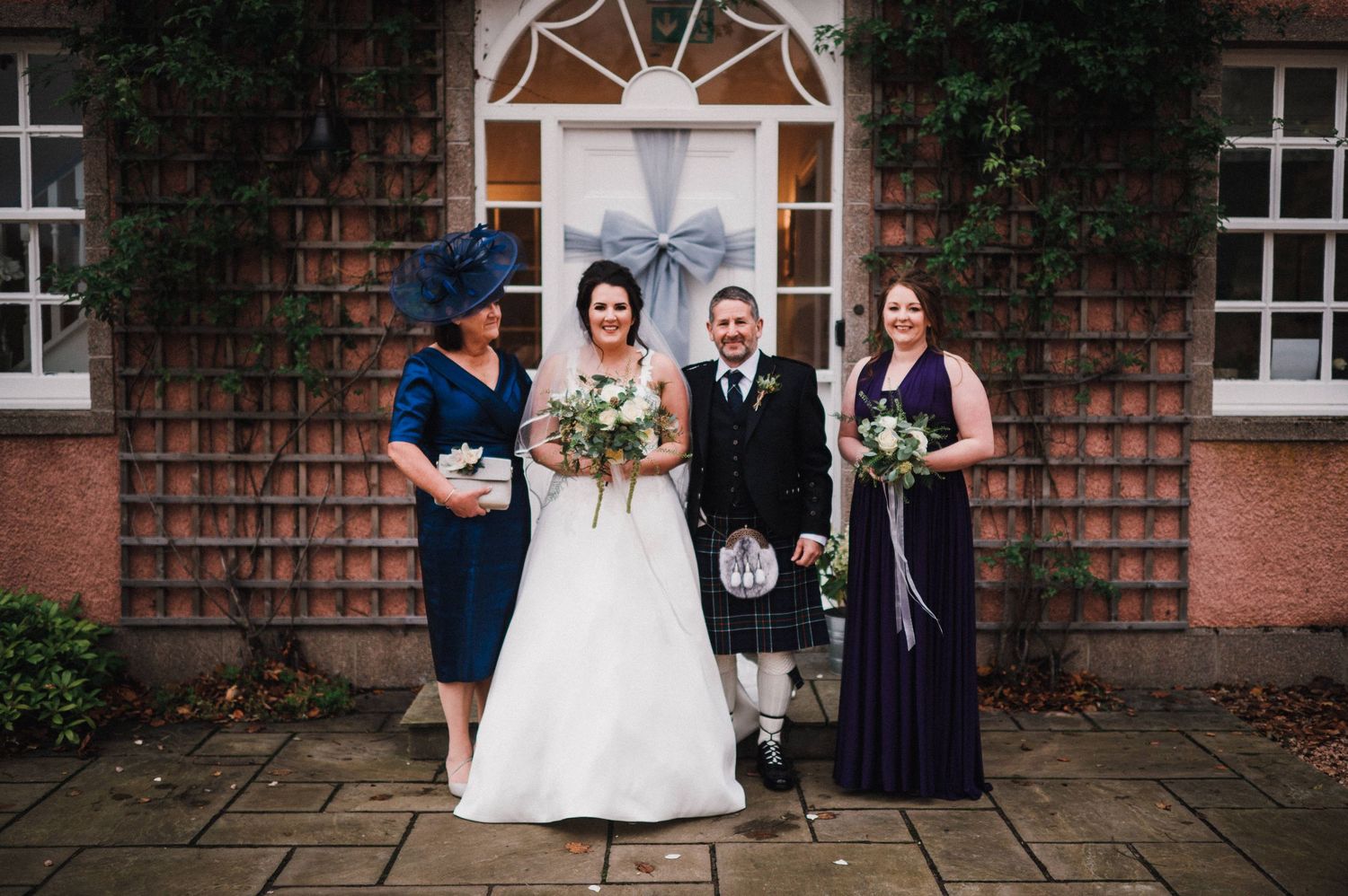 Wedding group portrait in front of a classic brick building with white trim.