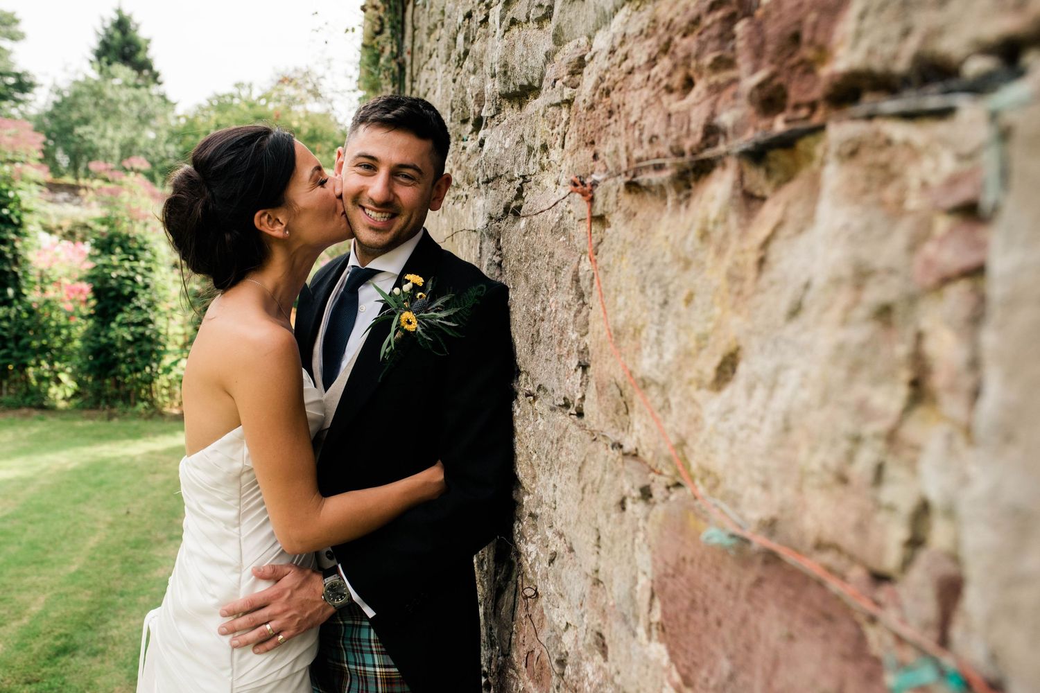 A tender moment captured against an ancient stone wall during a wedding.