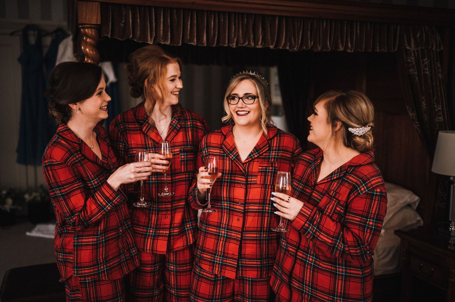 Group in matching red plaid pajamas sharing drinks and laughing together.