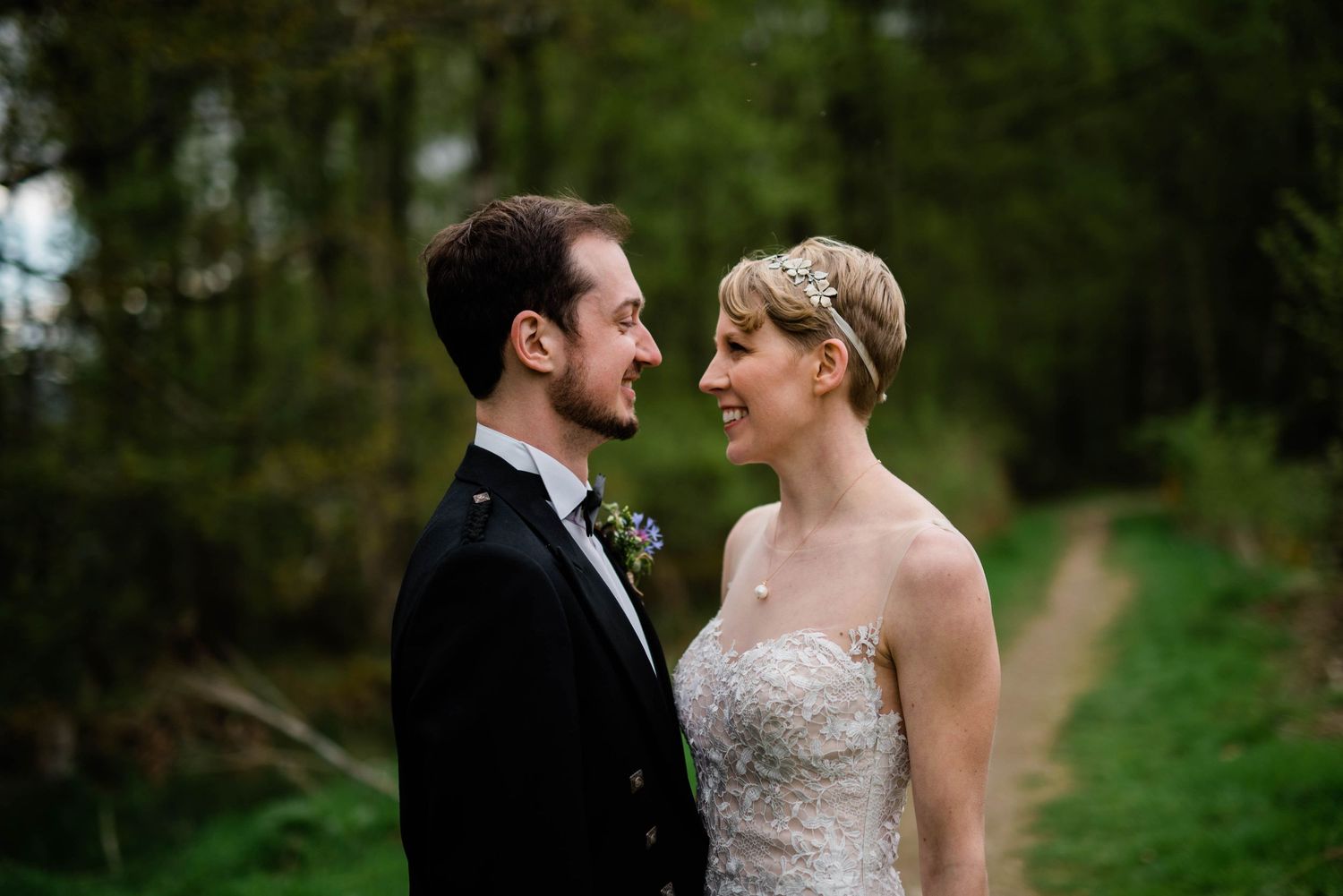 A romantic outdoor portrait of a couple in wedding attire against a lush green background.