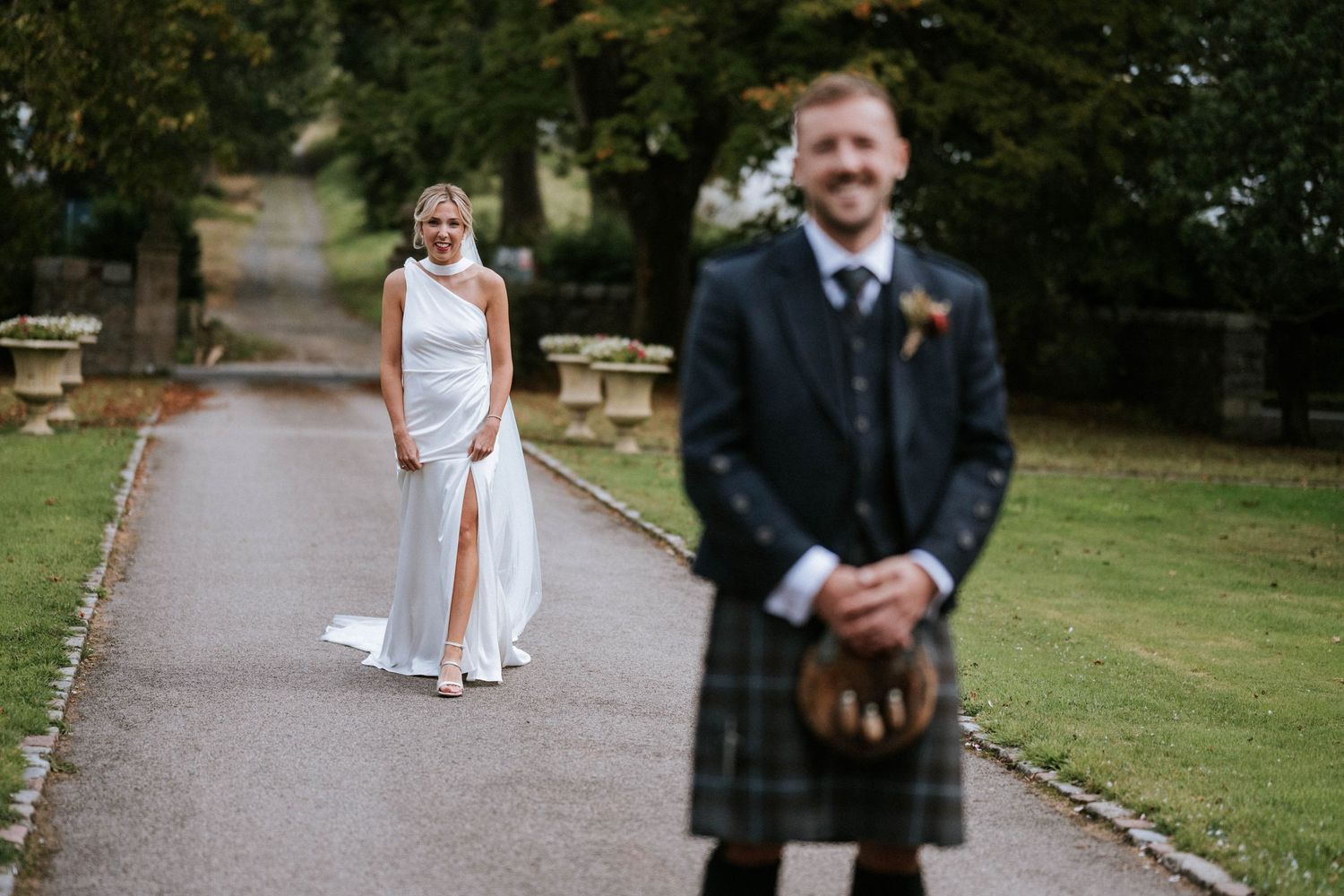 Wedding party walking along a garden path surrounded by greenery.