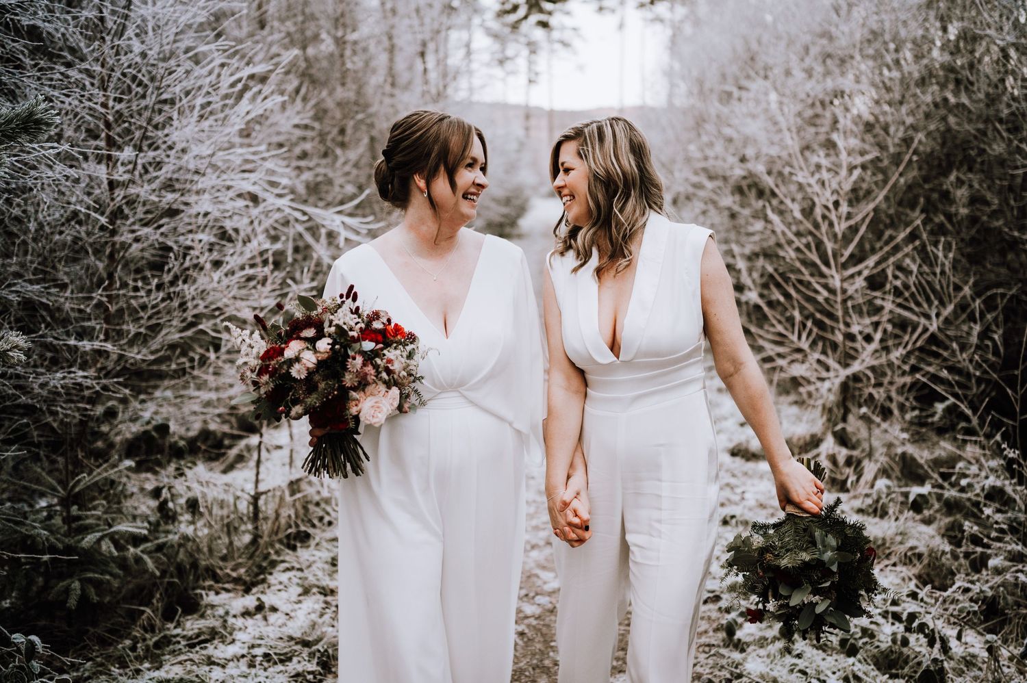 Same Sex Wedding Photography. Two figures in white hold hands while walking through a dreamy winter landscape.