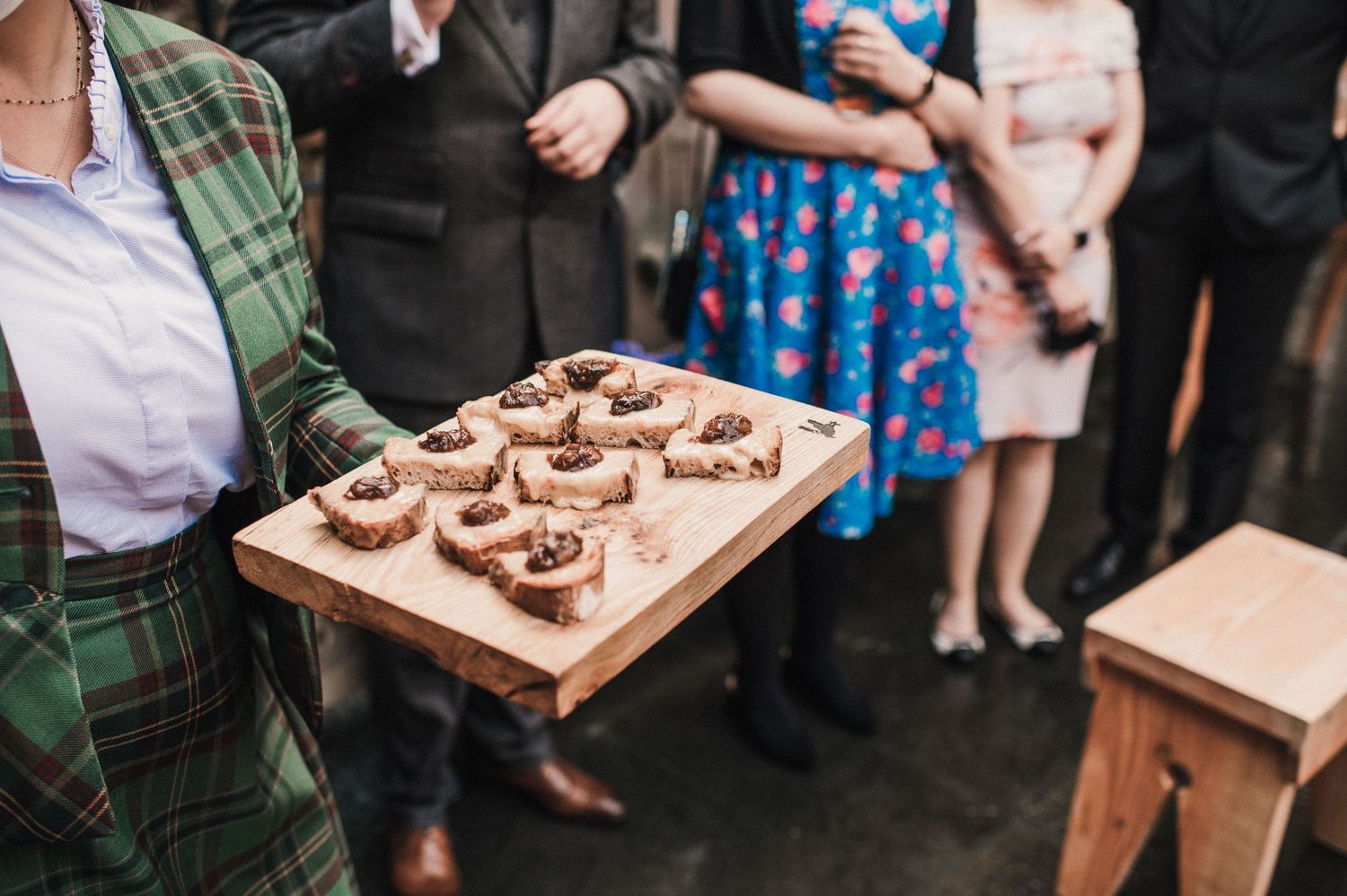 Wooden serving board with bite-sized desserts being presented at formal event.