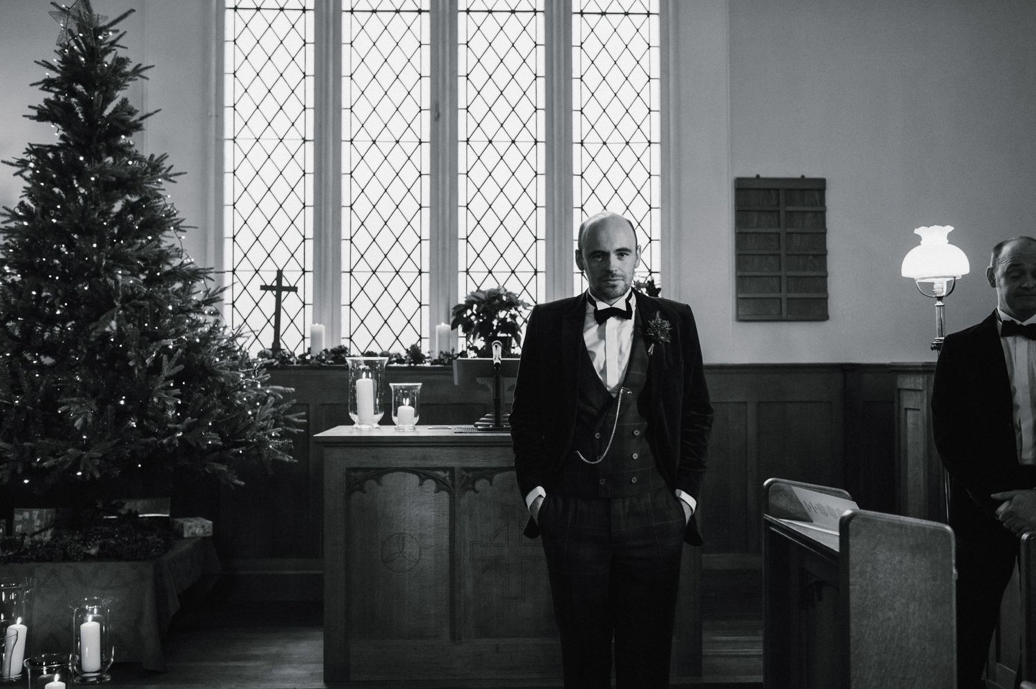 A formal gathering in a church with tall Gothic windows and a Christmas tree.