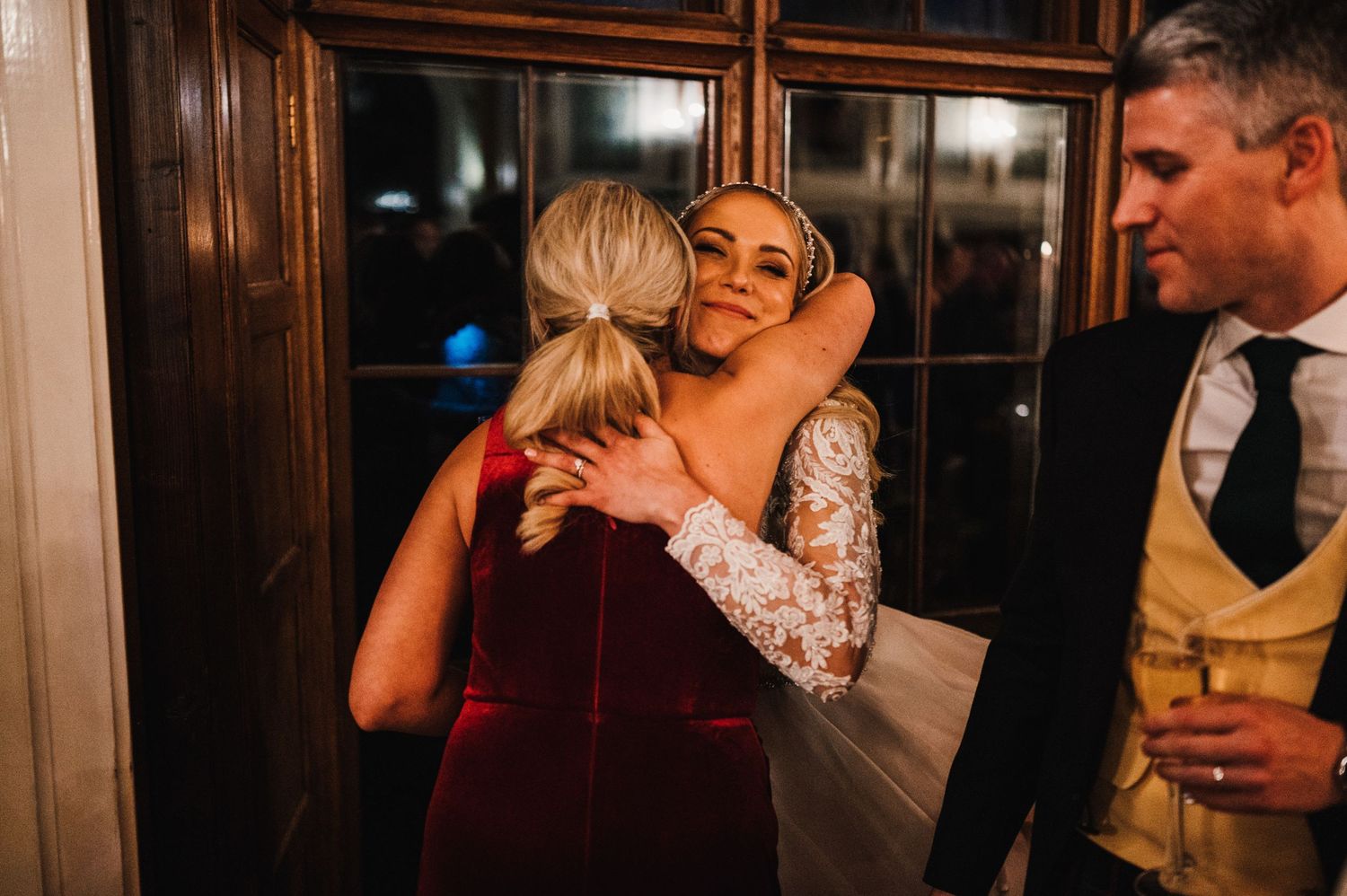 Guests share emotional embrace during evening wedding celebration.