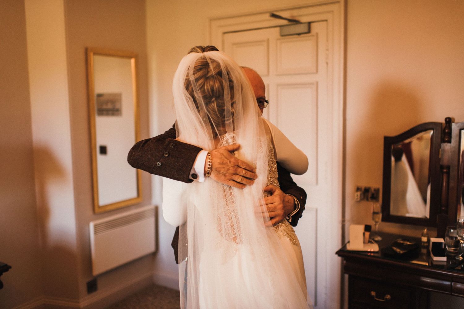 Tender embrace captured in warm tones during wedding preparations.