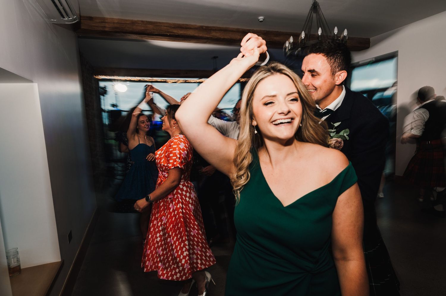 People dancing and celebrating at a party in a modern indoor venue with white walls.