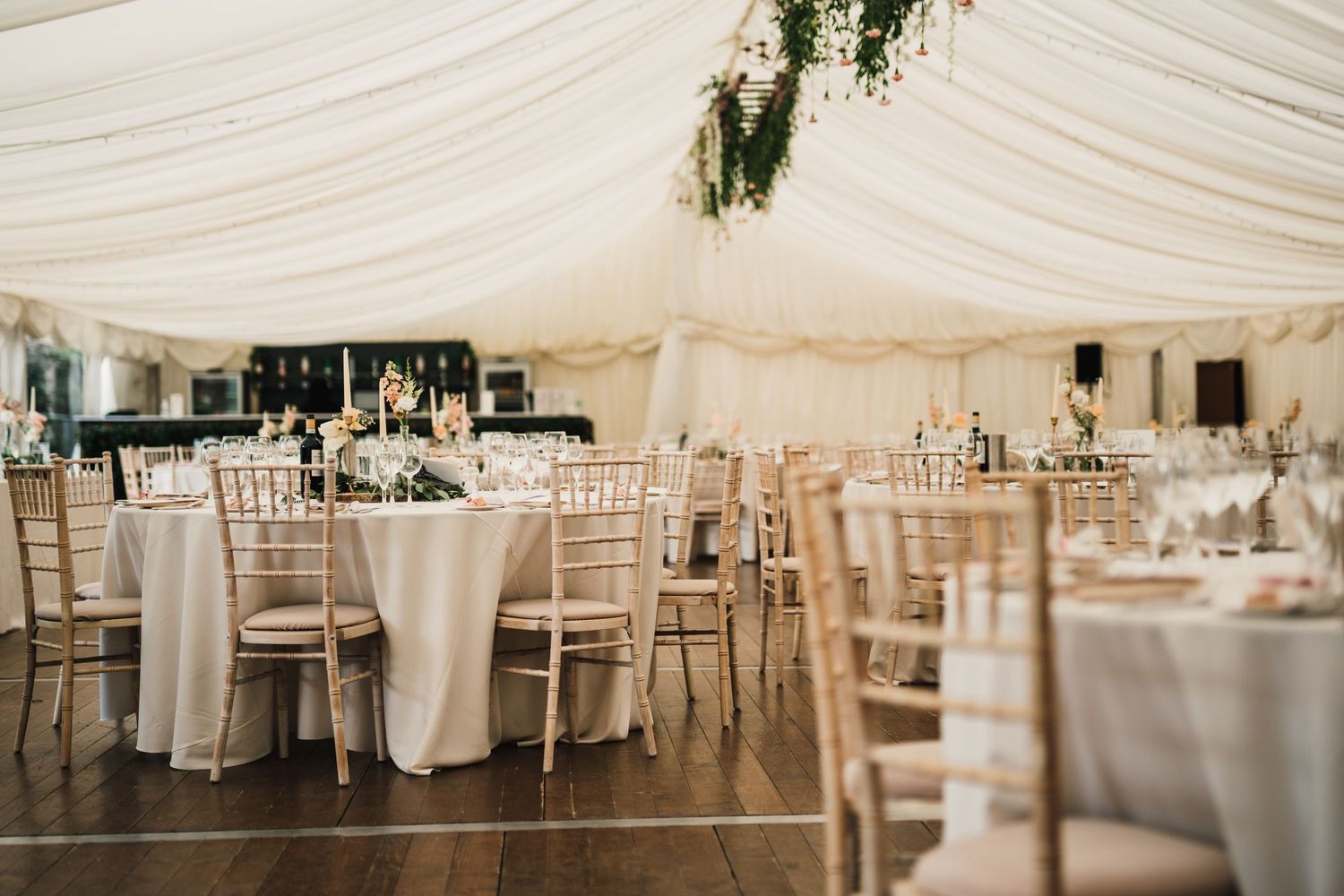 Elegant white marquee wedding reception with round tables and chiavari chairs.