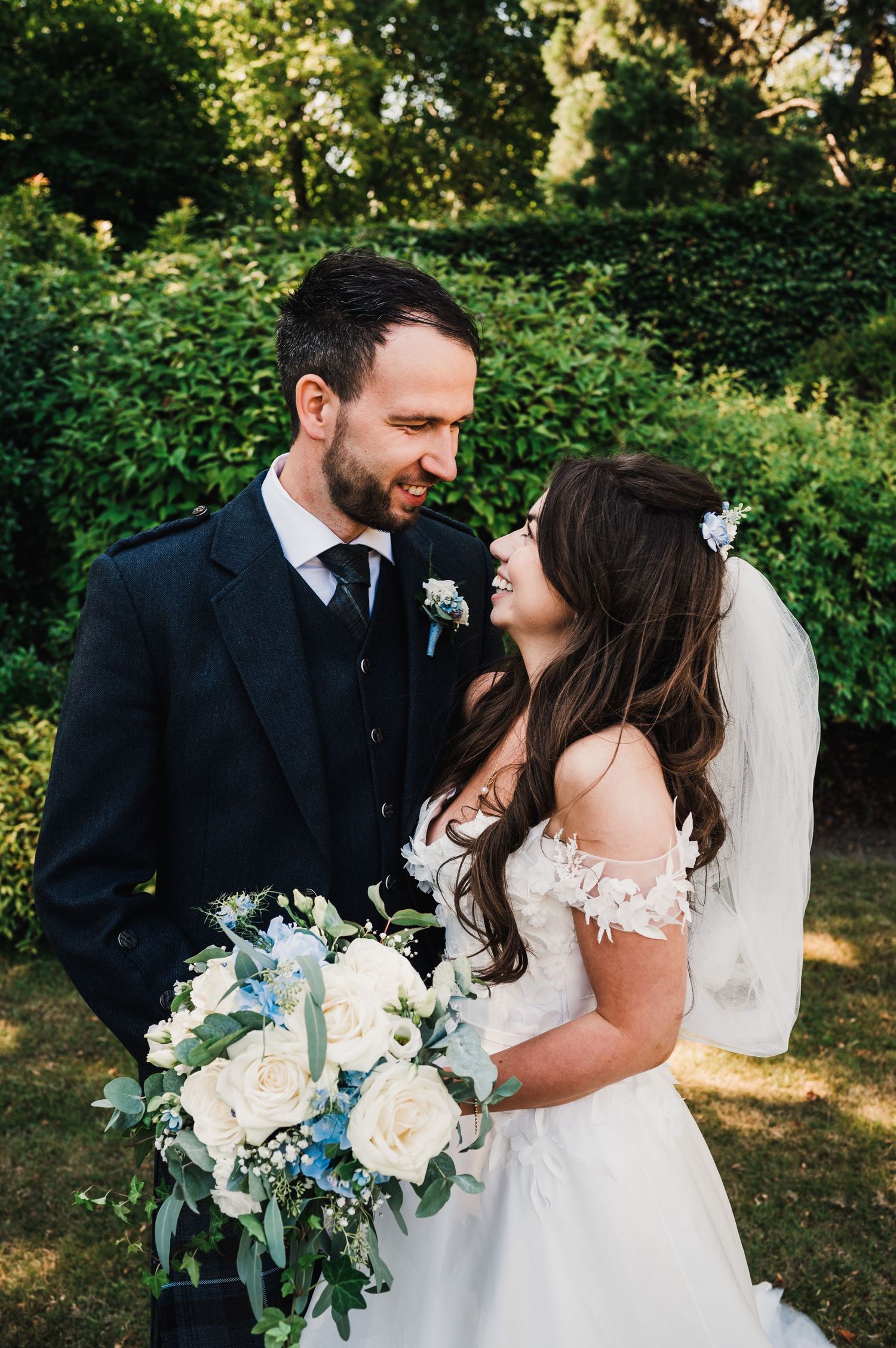 Romantic garden wedding portrait with elegant white bouquet and Scottish formal attire.