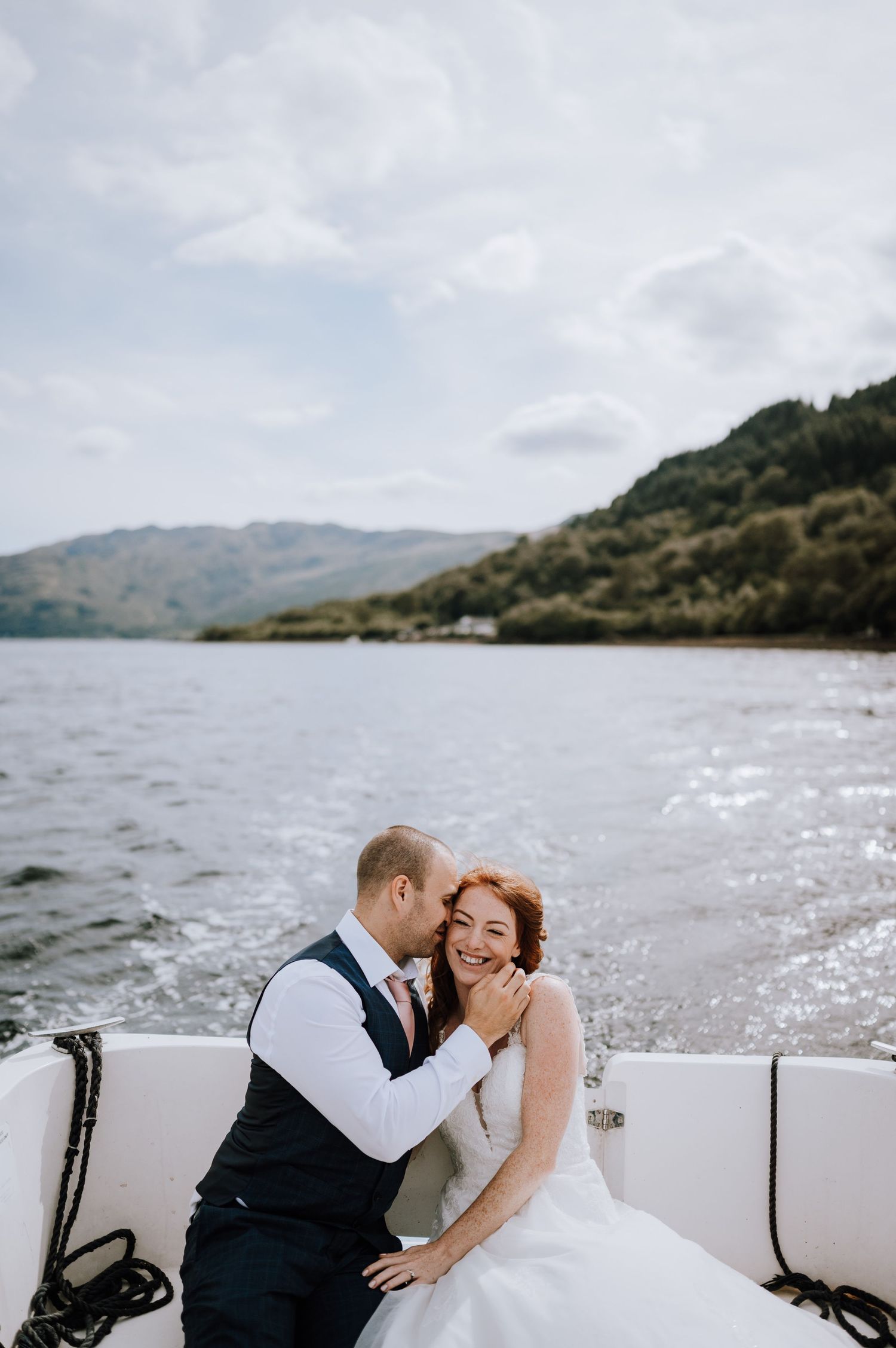 A romantic boat ride celebration on a serene lake surrounded by Scottish highlands.