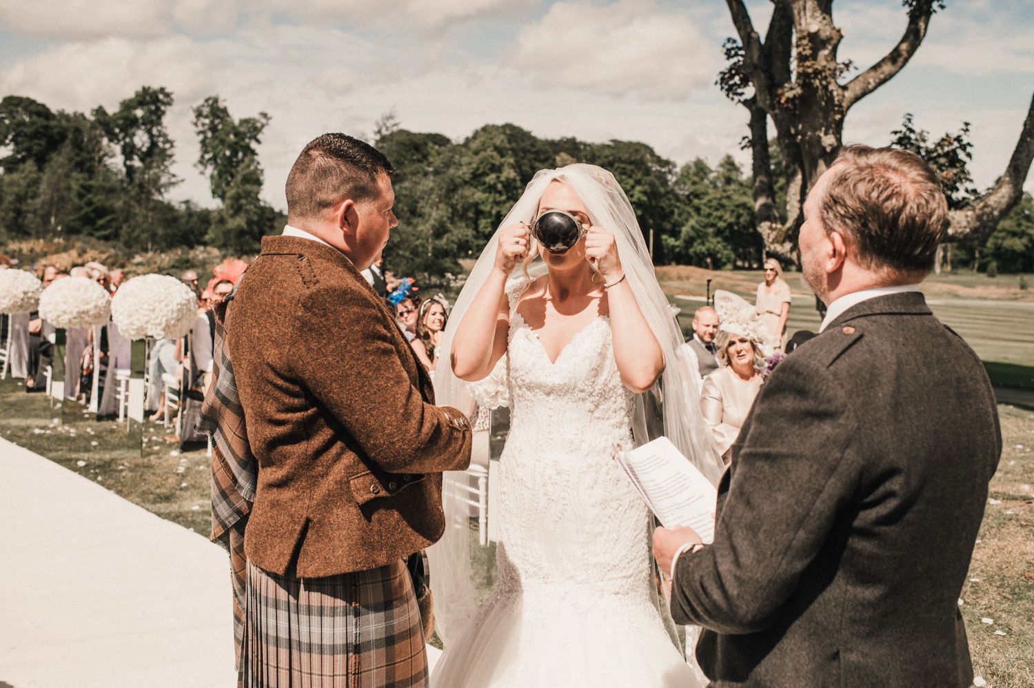 Wedding ceremony outdoors with Scottish traditional dress and emotional exchange.