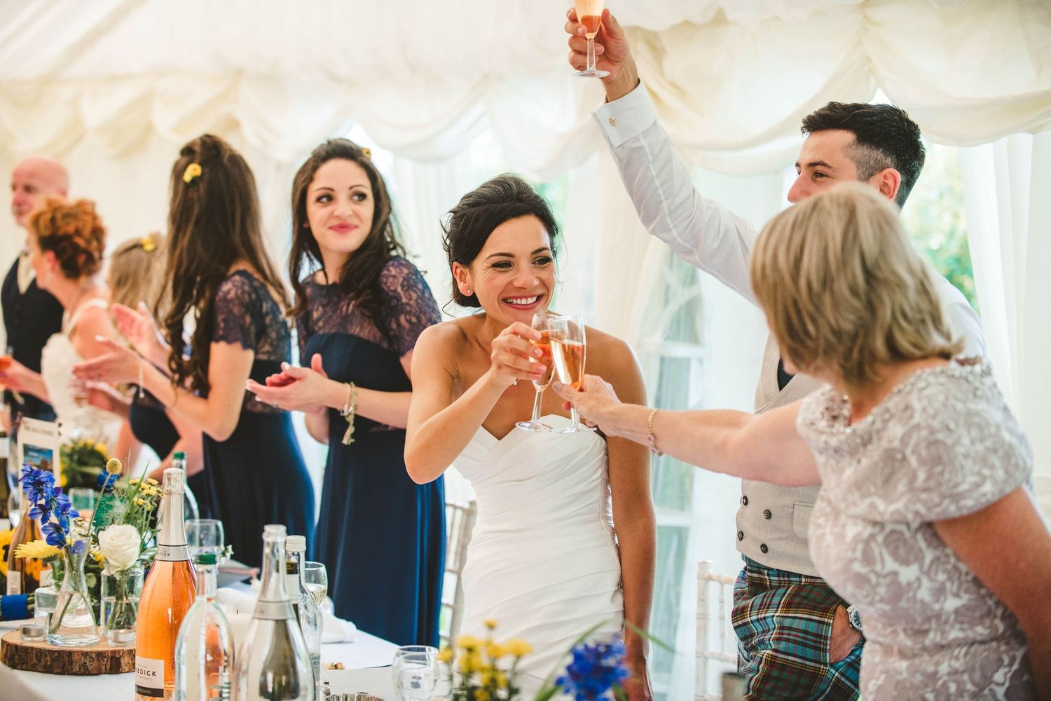 Wedding guests raising glasses for a toast during reception celebration.