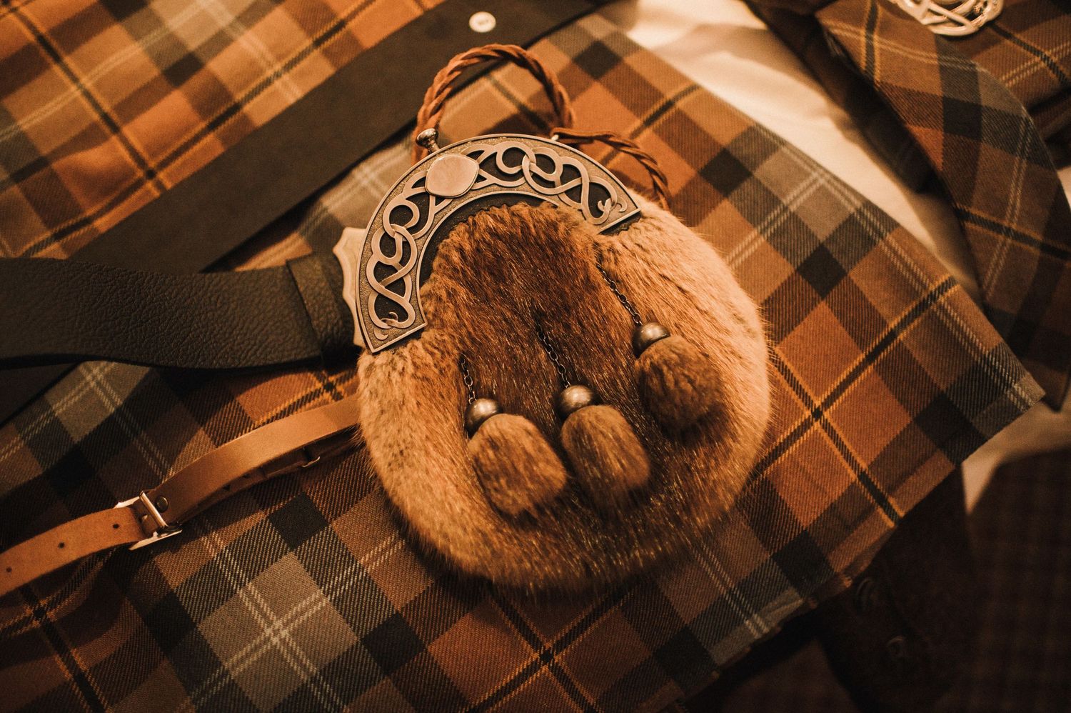 Traditional Scottish sporran with fur detail lies on tartan fabric.