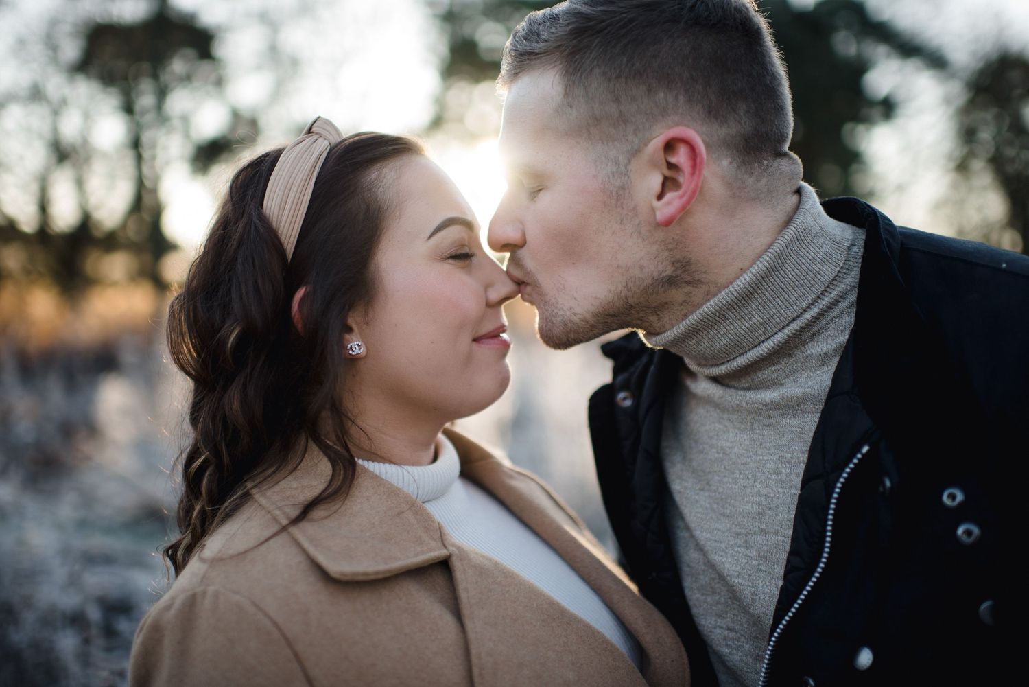 A tender moment between a couple during a winter photoshoot with frost-covered scenery.