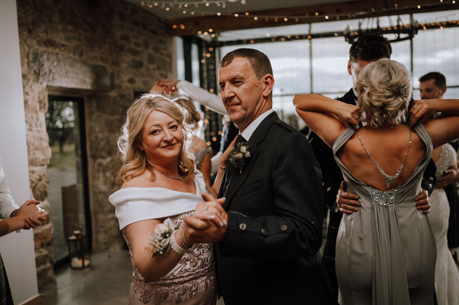 Wedding guests enjoying celebrations in an industrial-chic venue with exposed stone walls.