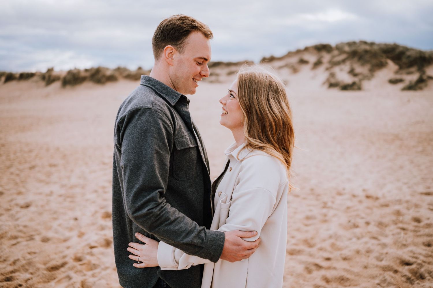 Intimate moment between couple embracing on a sandy beach.