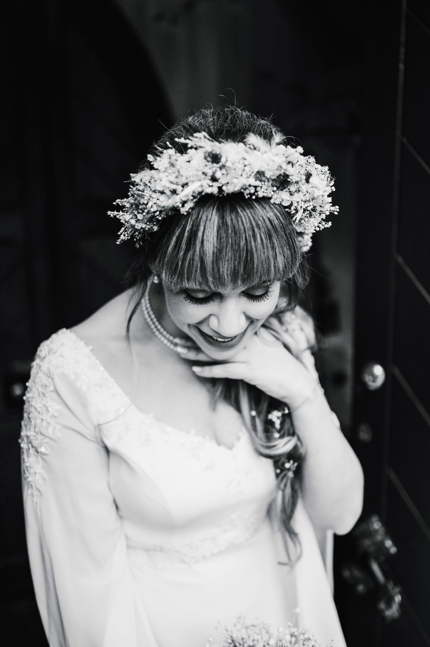 Black and white portrait of bride wearing floral crown laughing with natural joy.
