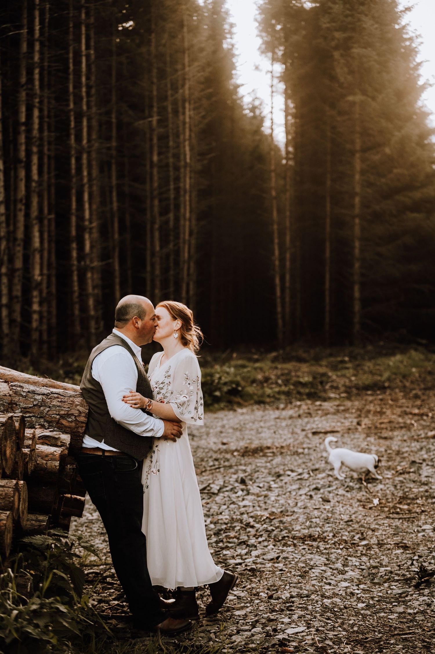 Intimate forest wedding moment captured with tall pine trees in background.