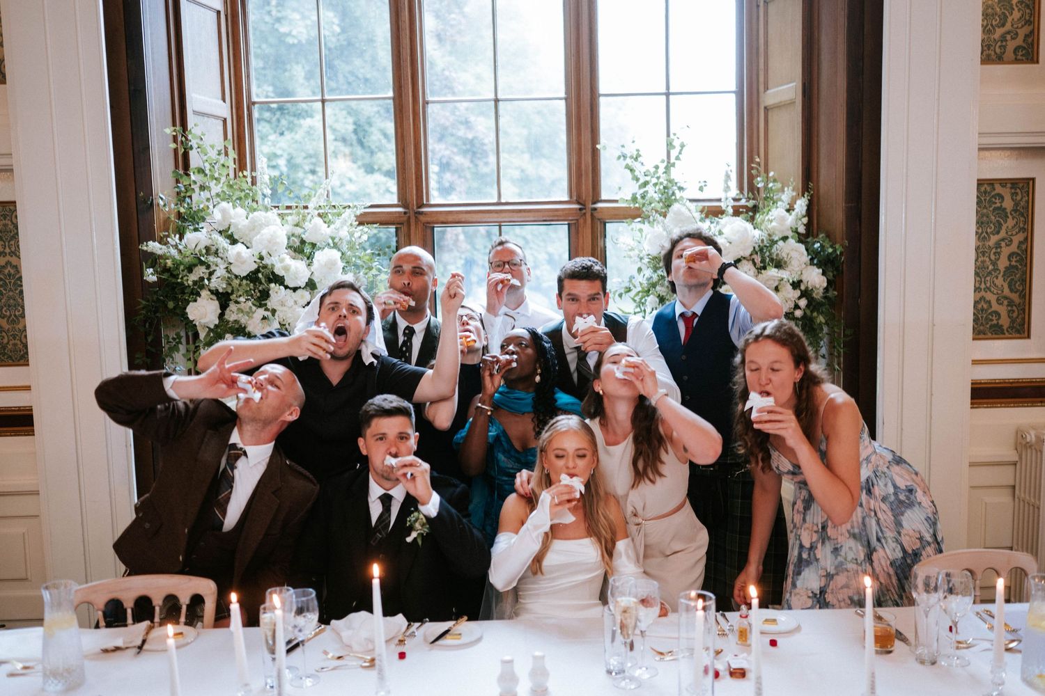 Wedding guests celebrate with animated expressions during reception dinner at an elegant venue.