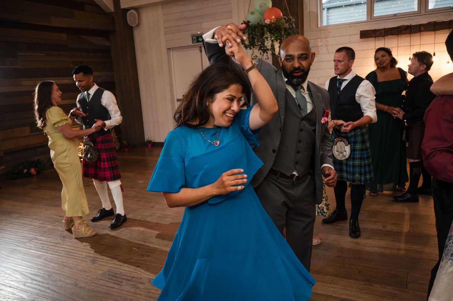 Wedding guests mingle and socialize in rustic wooden venue space.