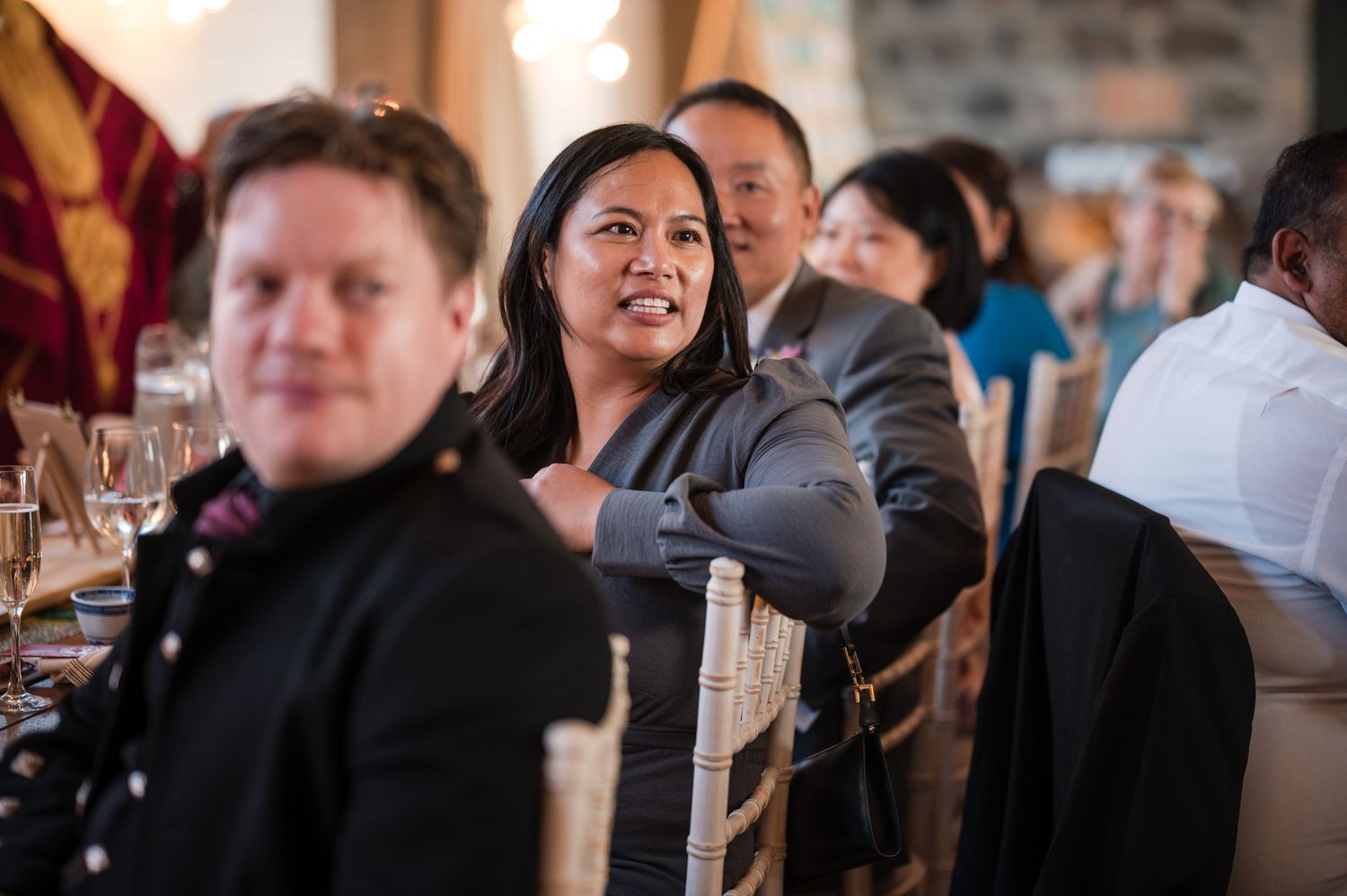 Wedding reception guests seated at tables in rustic indoor venue.