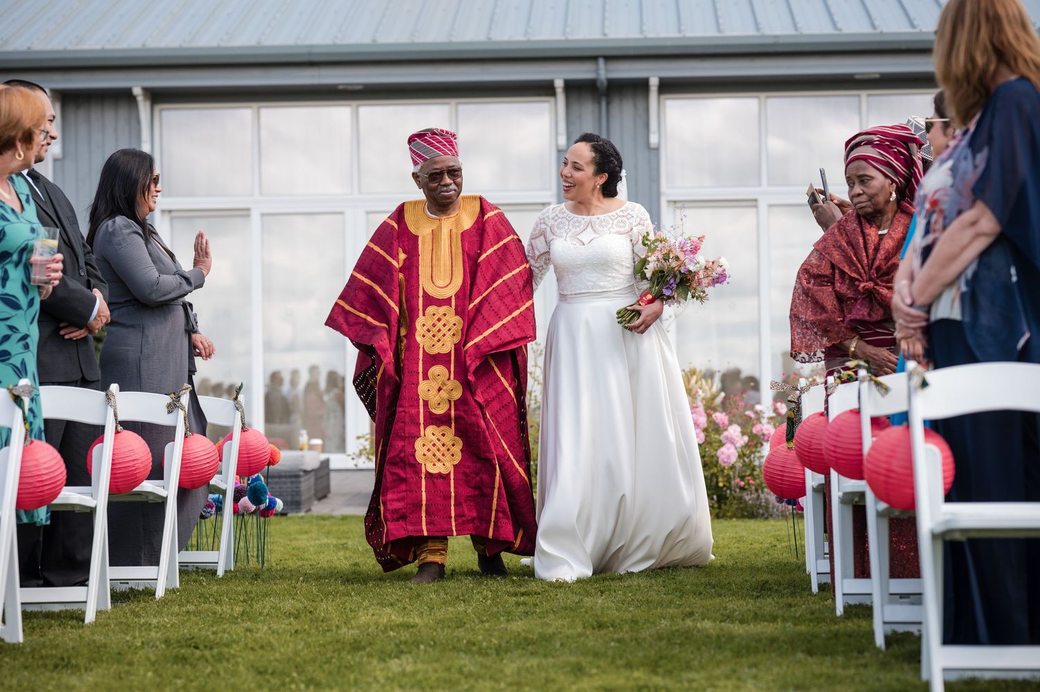 Wedding ceremony setup with white chairs and burgundy-robed officiant outdoors.