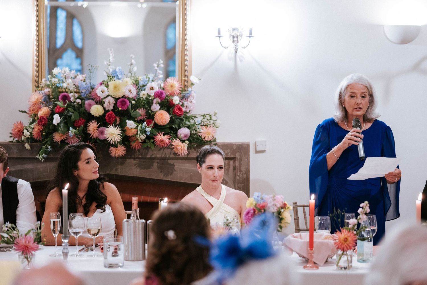 Elegant wedding reception setup with blue stained glass windows and pink floral arrangements.