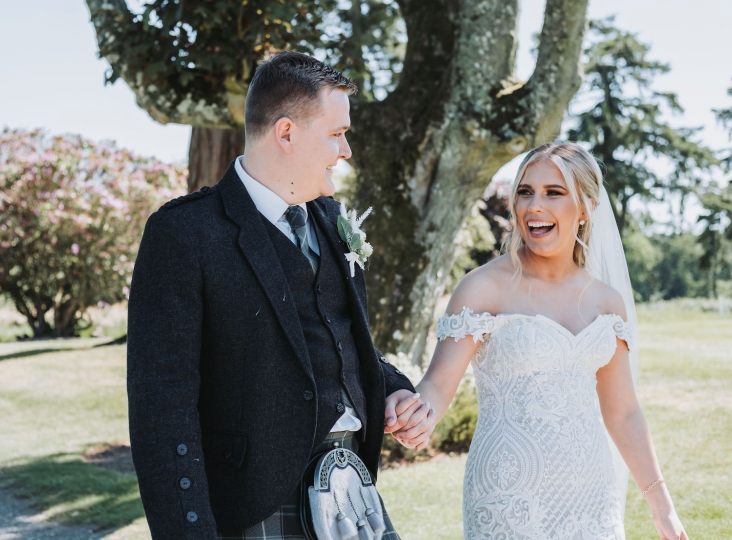 A happy couple shares joyful moments together during their outdoor wedding photoshoot in a scenic garden setting.