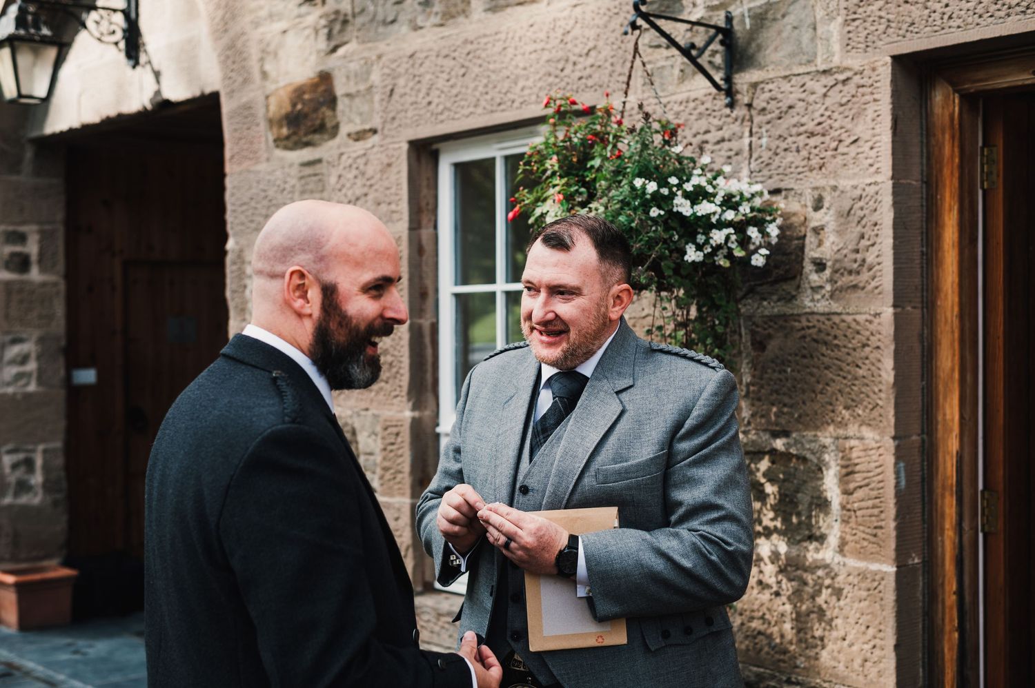 Wedding party members gathered outside a traditional stone building.