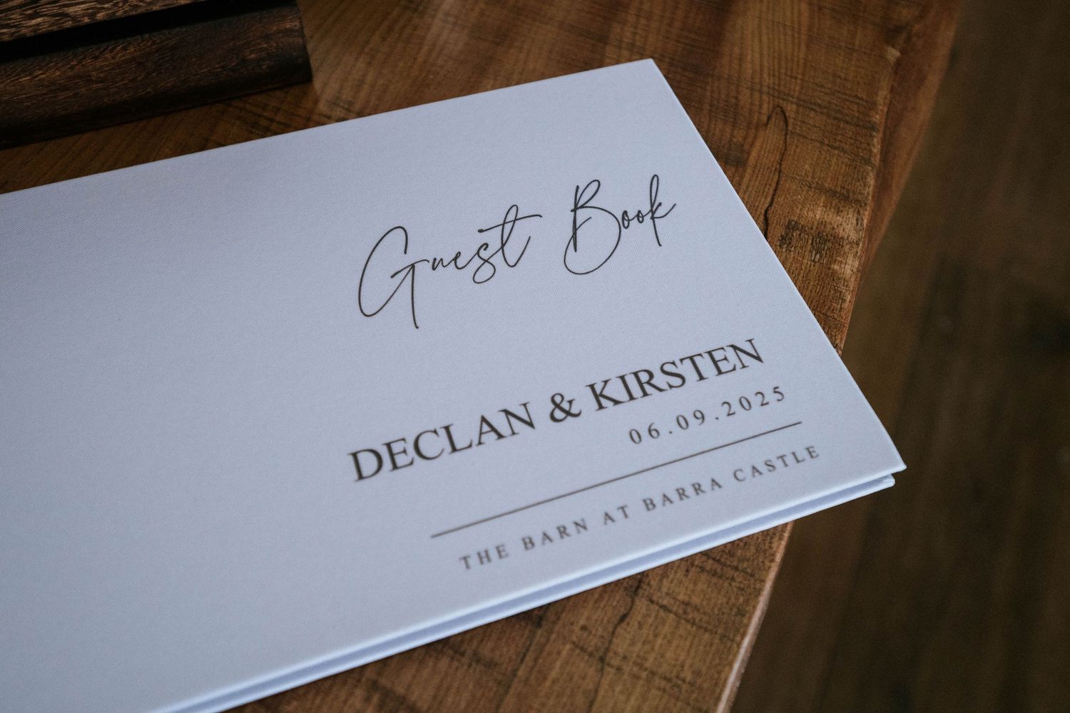 Elegant wedding guest book or menu cards with modern calligraphy displayed on wooden surface.