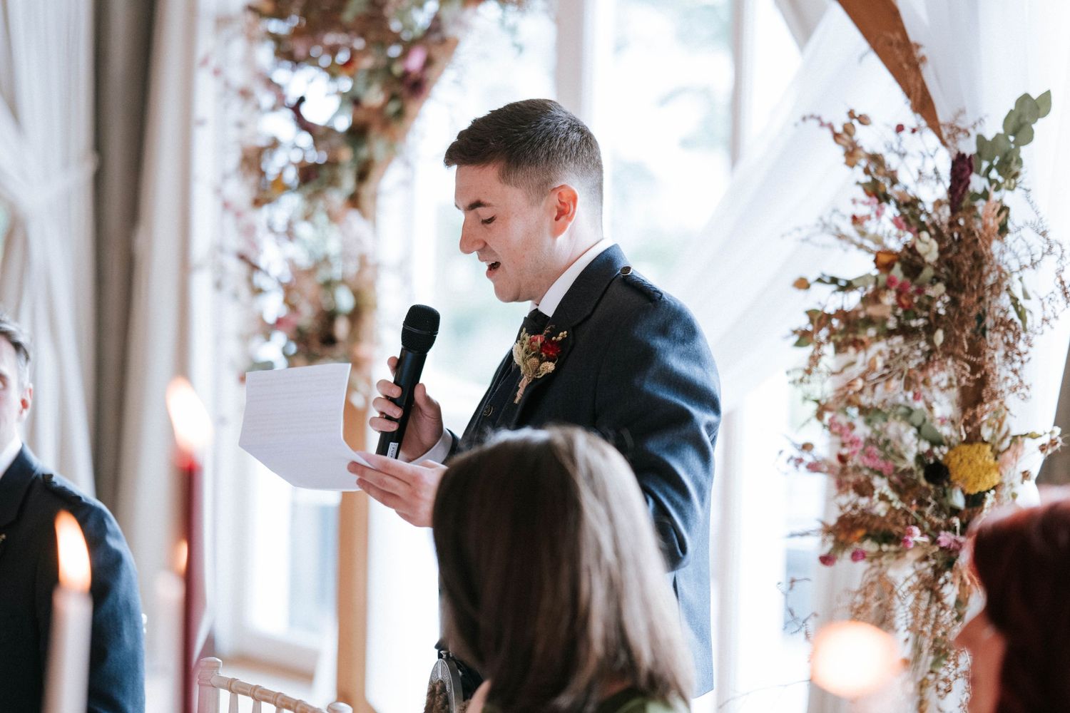 Wedding ceremony decor features dried floral arrangements in an indoor venue with natural light.
