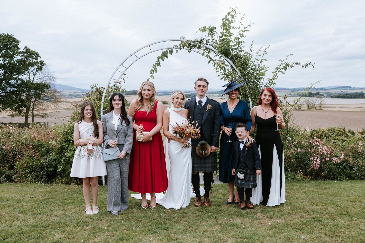 Wedding party poses outdoors against a scenic coastal backdrop.