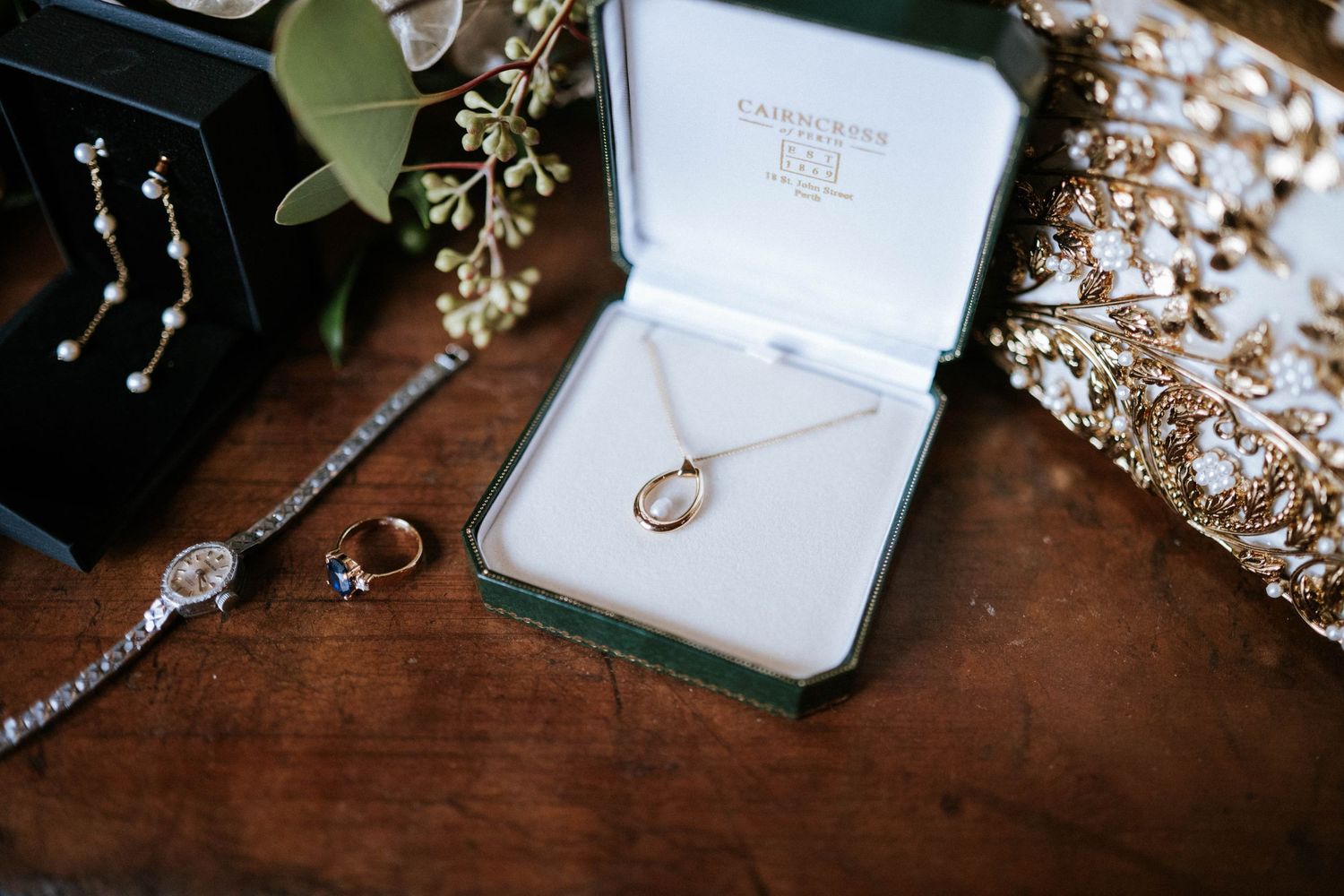 Wedding jewelry and accessories including rings and hair pieces arranged on dark wooden surface.