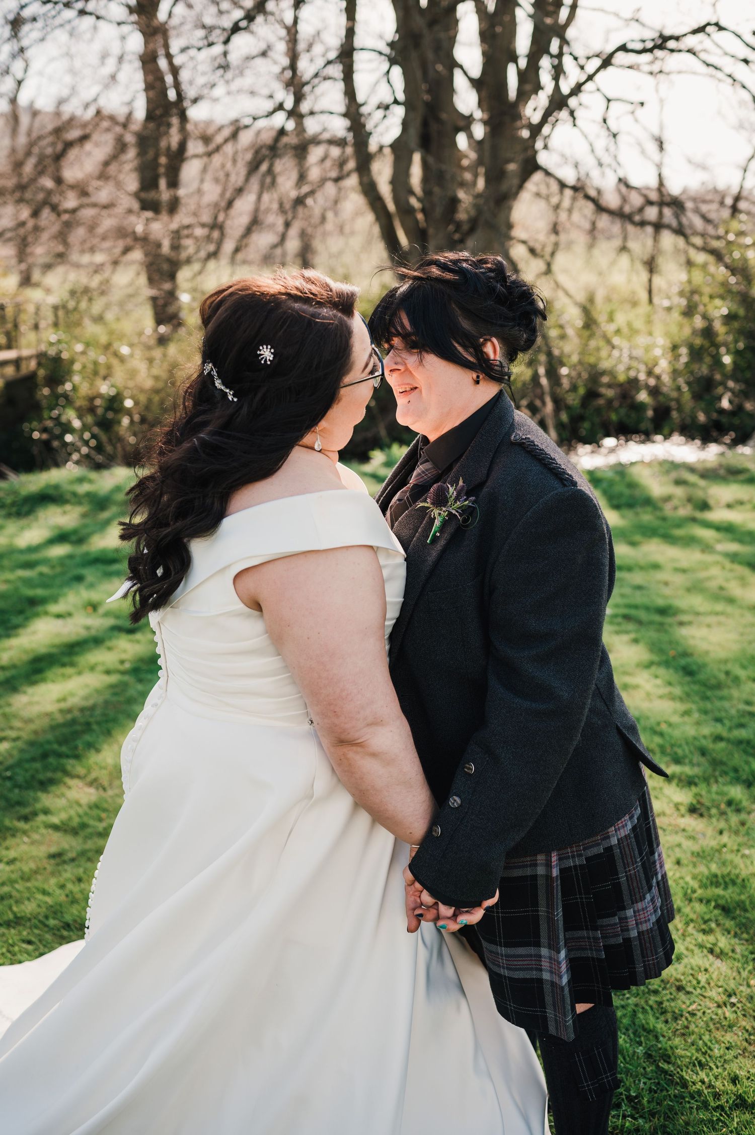 Logie House Wedding Photography. A tender wedding moment captured in a sunlit garden with spring greenery in the background.