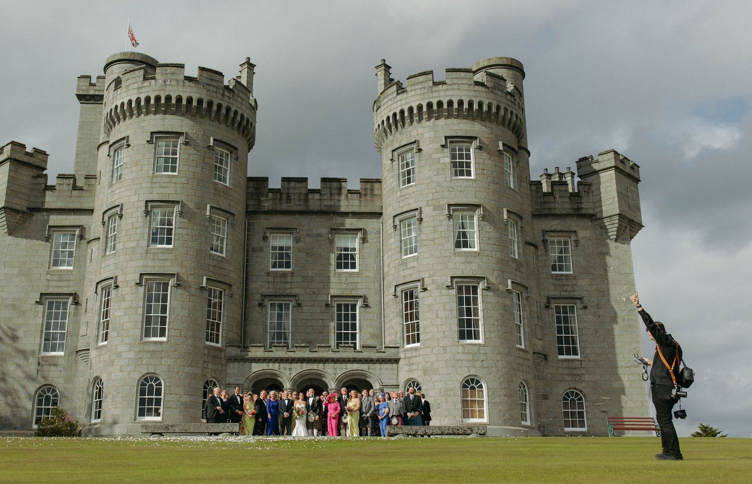 Panoramic view of a historic Scottish castle with gray stone towers and turrets against a cloudy sky.