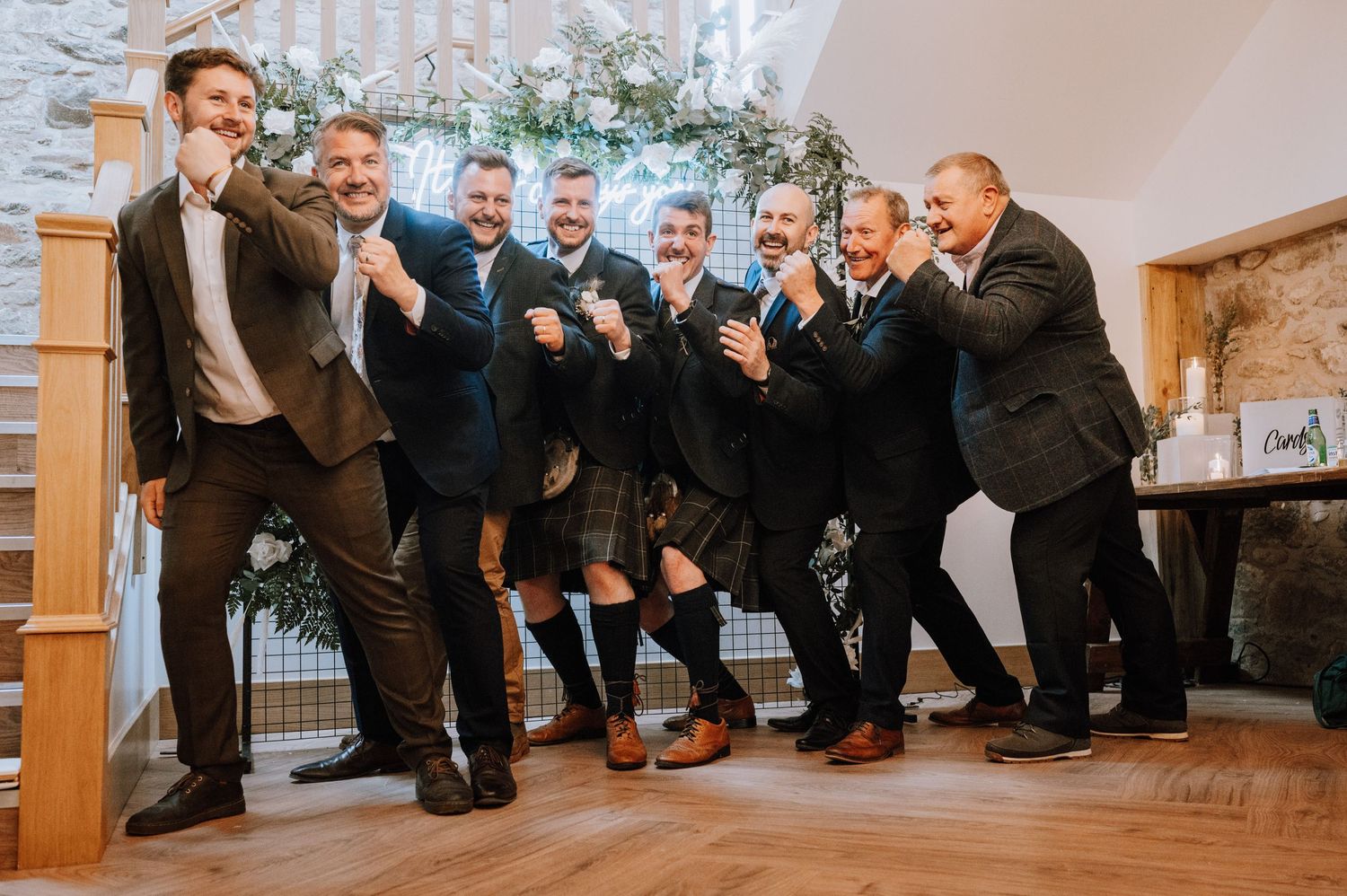Groomsmen strike playful poses for a group photo at wedding reception.