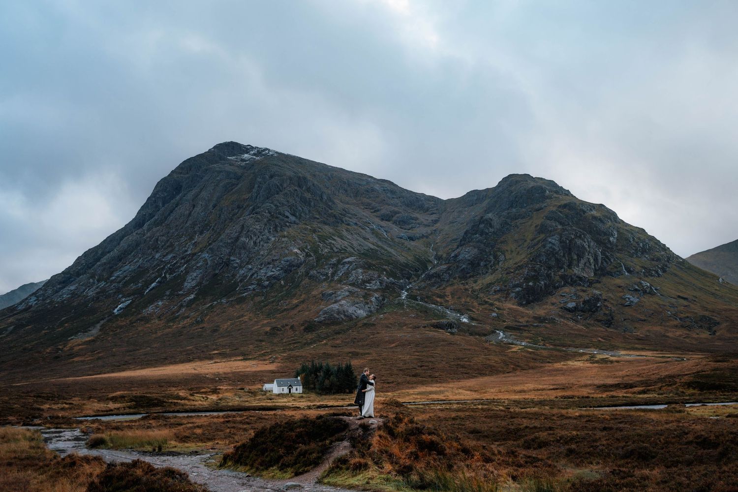 Panoramic view of rugged Scottish Highland mountains under moody cloudy skies.