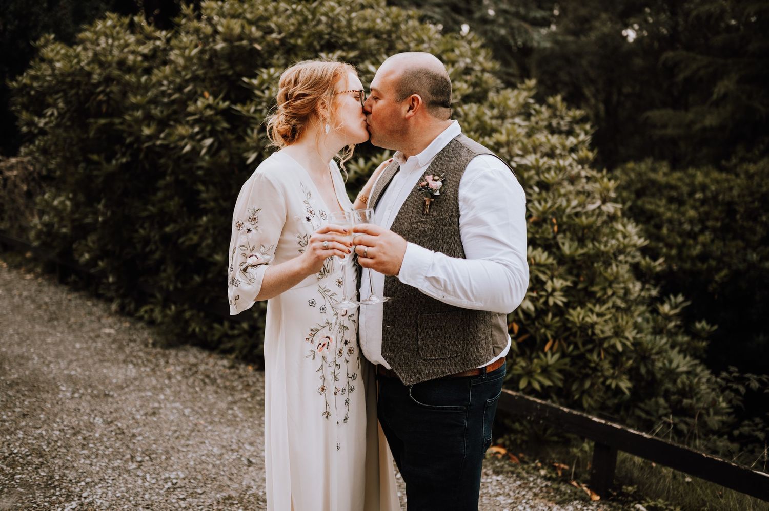 Couple sharing drinks and laughter in outdoor wedding celebration.