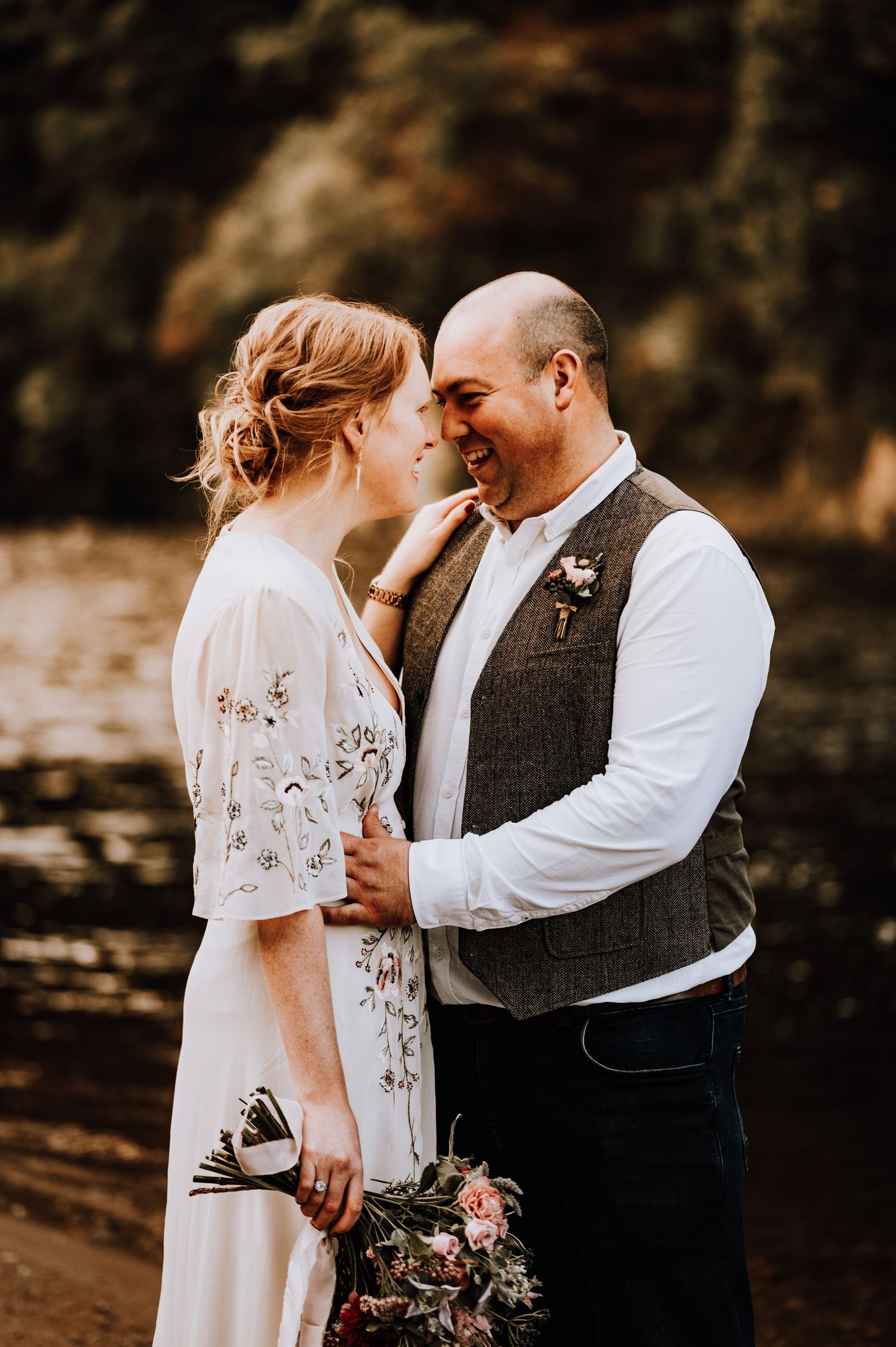 A romantic moment captured between a couple in wedding attire against an autumn backdrop.