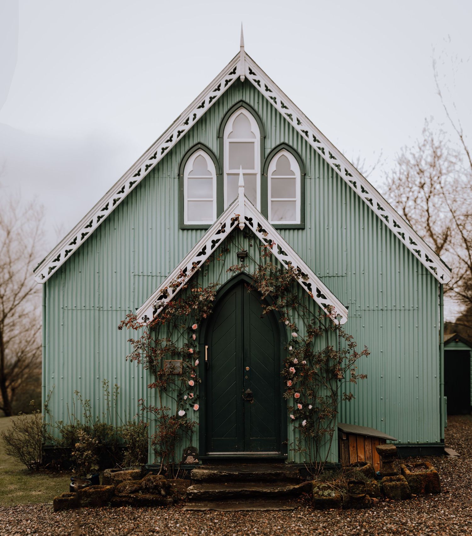 A charming mint-colored chapel with Gothic architecture and decorative white trim.