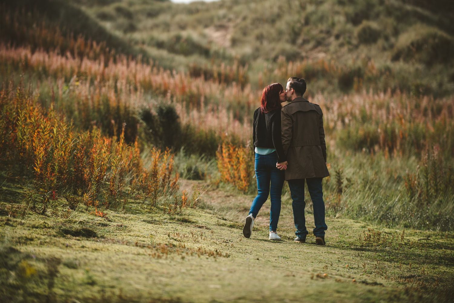 A couple walking together on a trail surrounded by autumn foliage.
