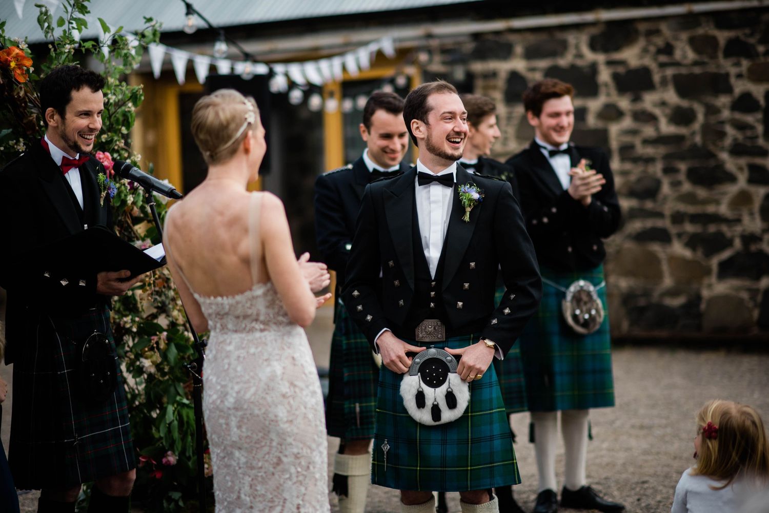A joyful moment during a Scottish wedding ceremony with groomsmen in kilts.