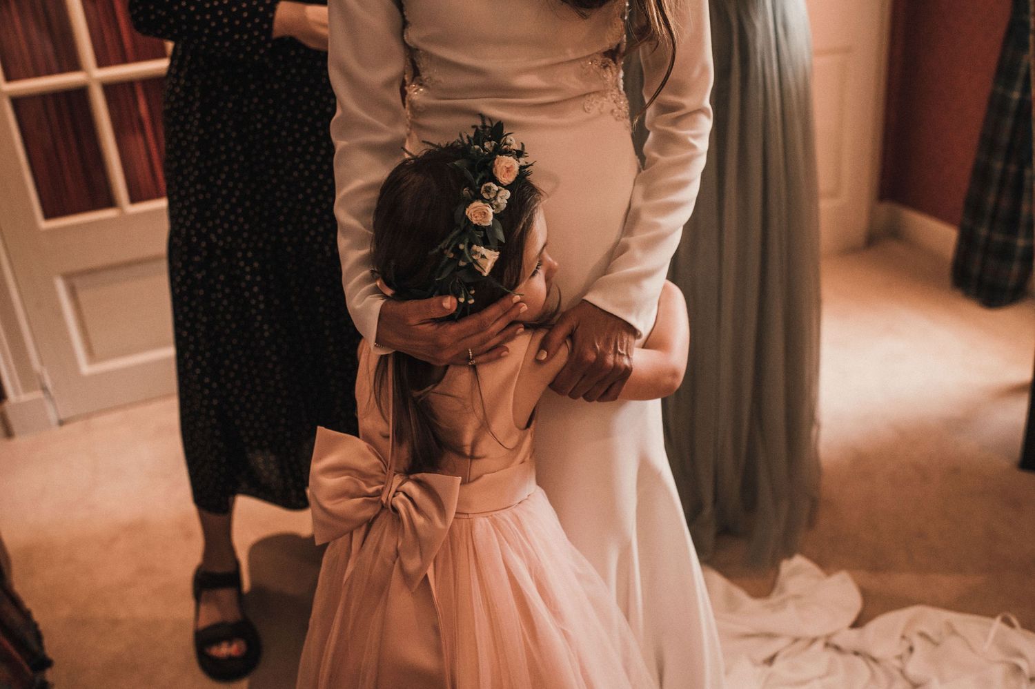Pink dress with a large bow being adjusted during a wedding preparation.