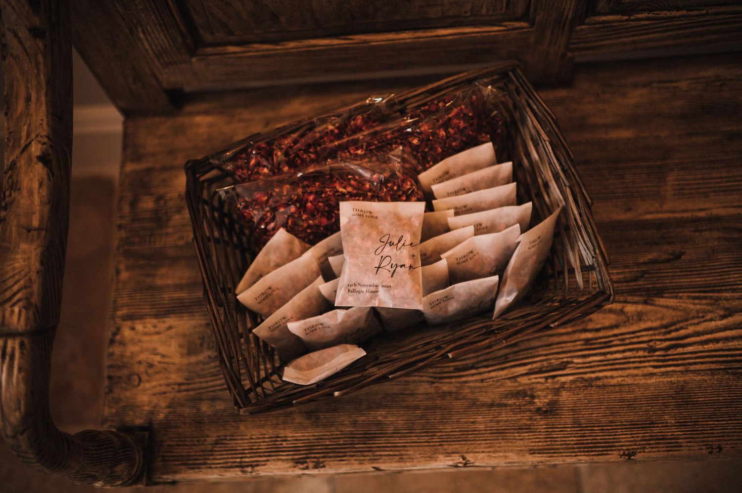 A rustic wooden basket filled with wrapped gifts and favors on a dark wooden surface.