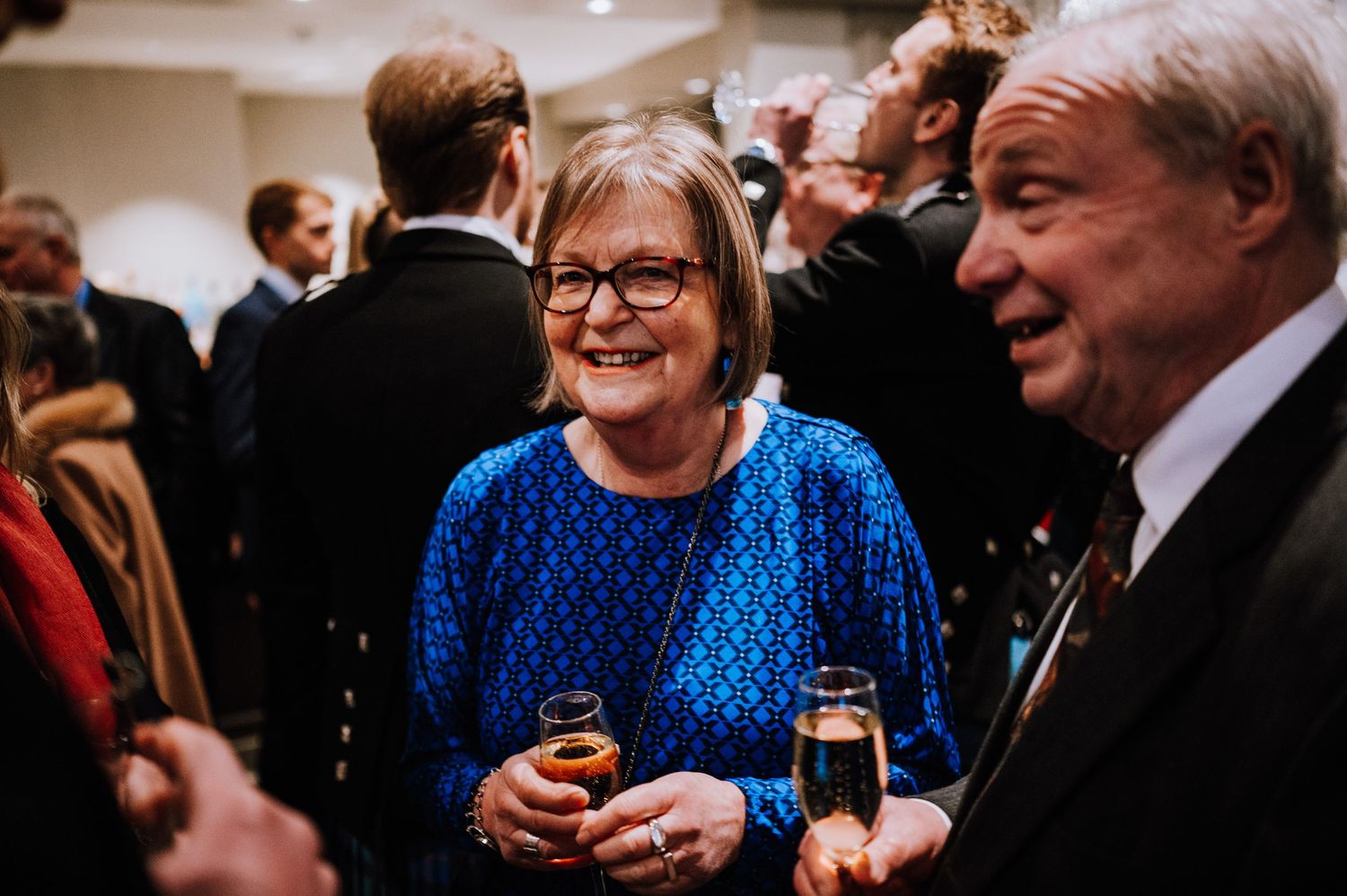 Wedding guests mingling and enjoying drinks during an indoor reception celebration.
