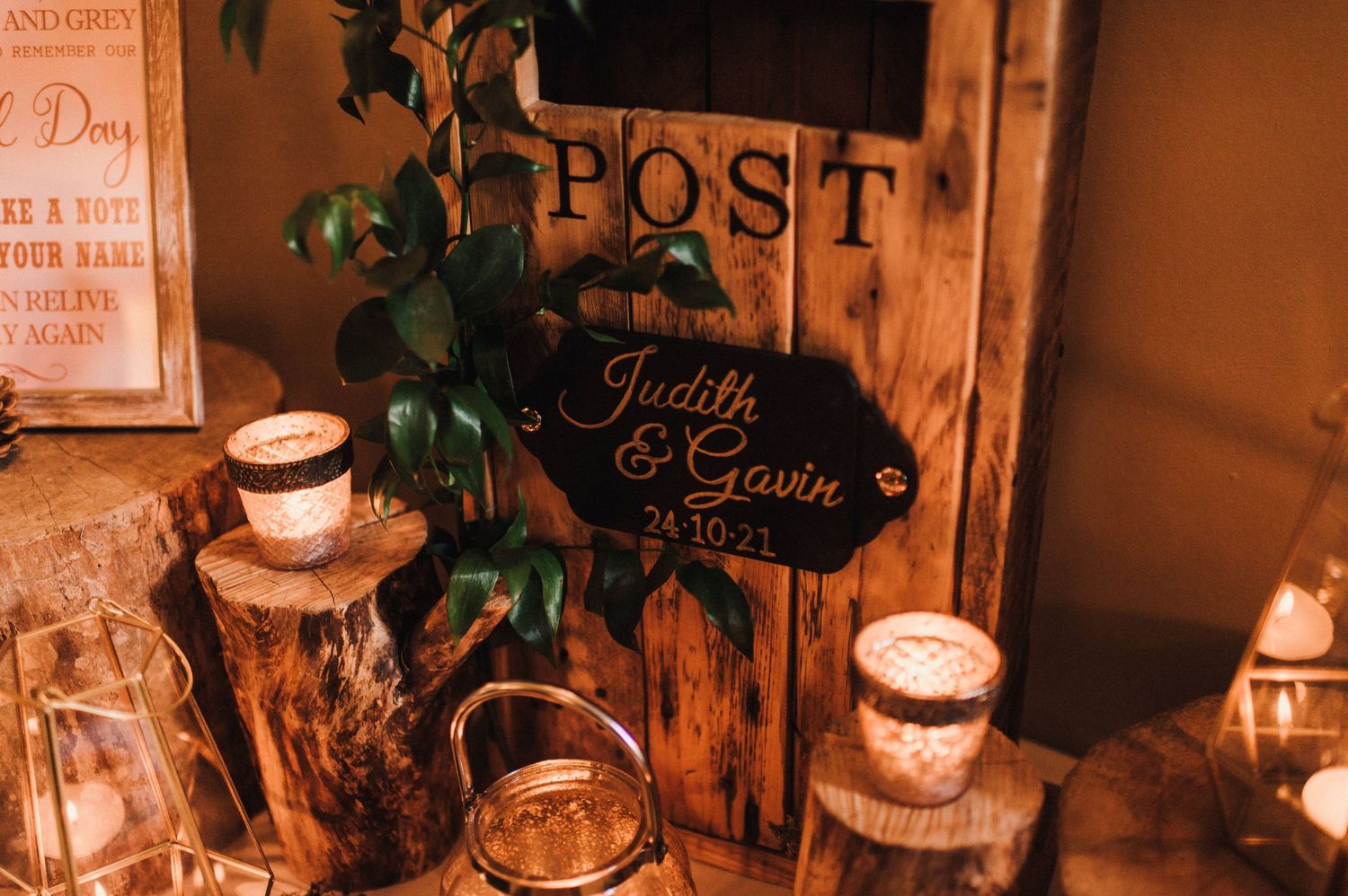 Rustic wedding post box setup with glowing candles and wooden decorative elements.