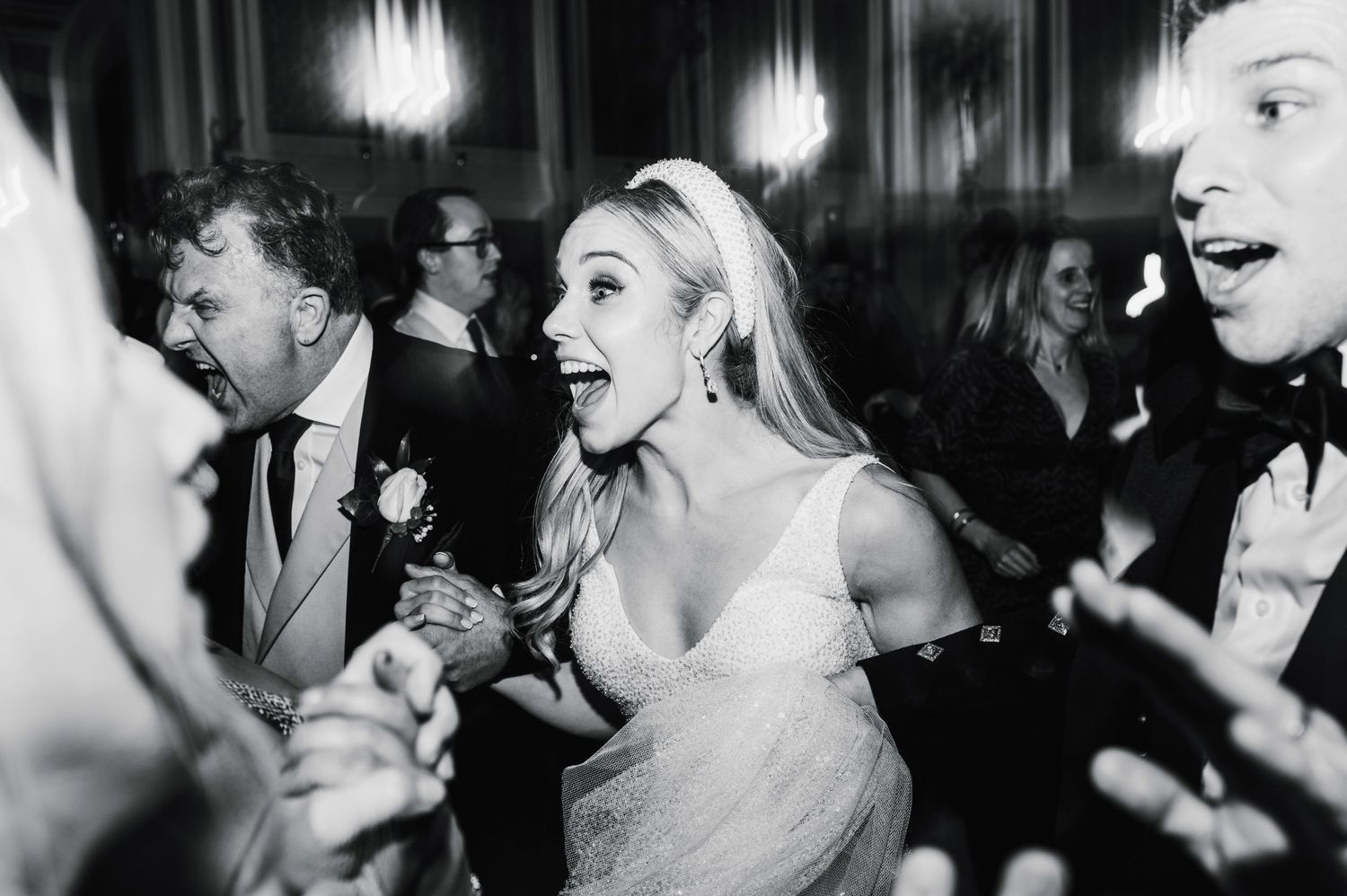 Black and white photo capturing energetic dancing and celebration at a wedding reception.