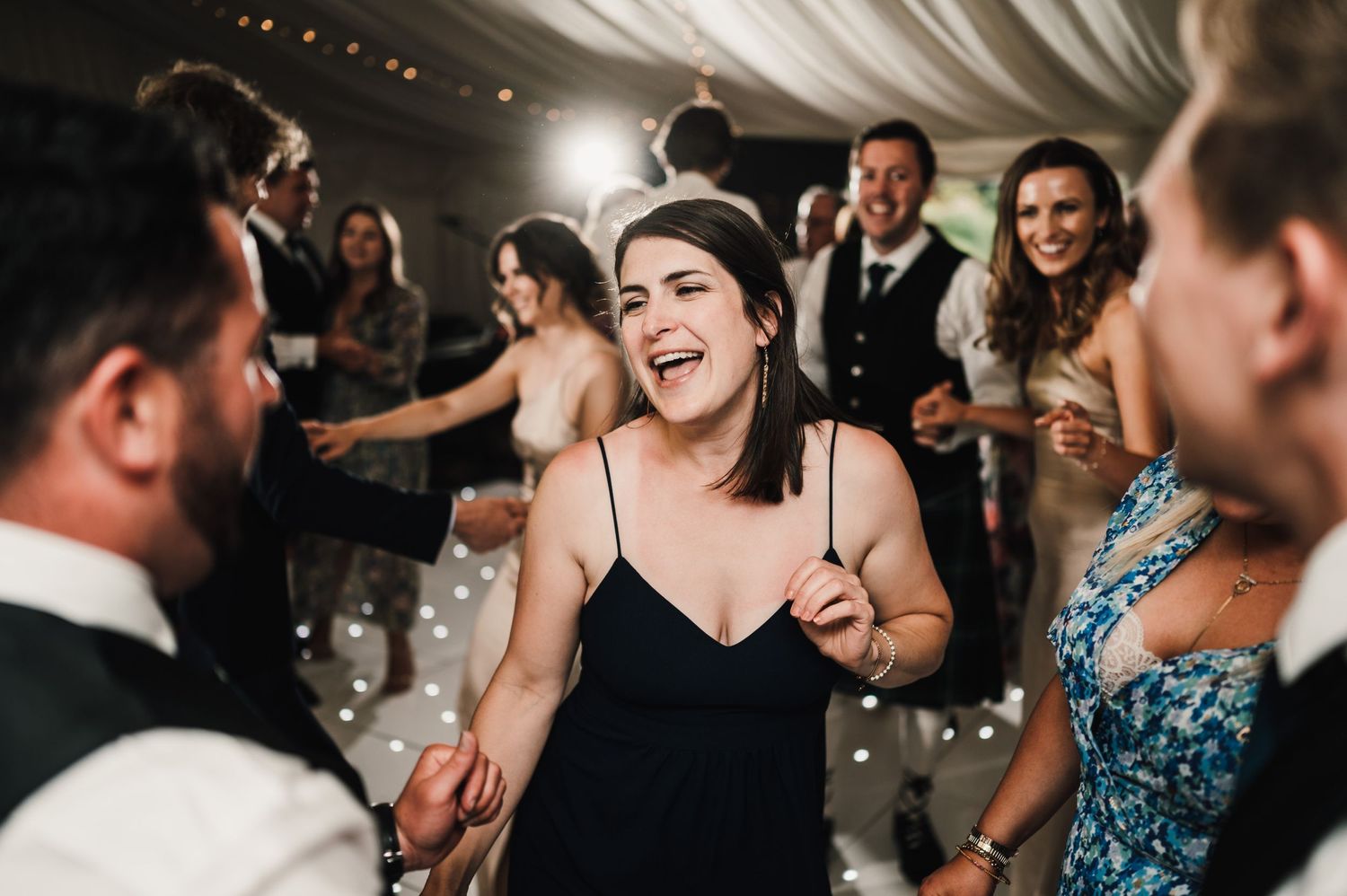 Candid moment of wedding guests laughing and dancing at a lively reception.
